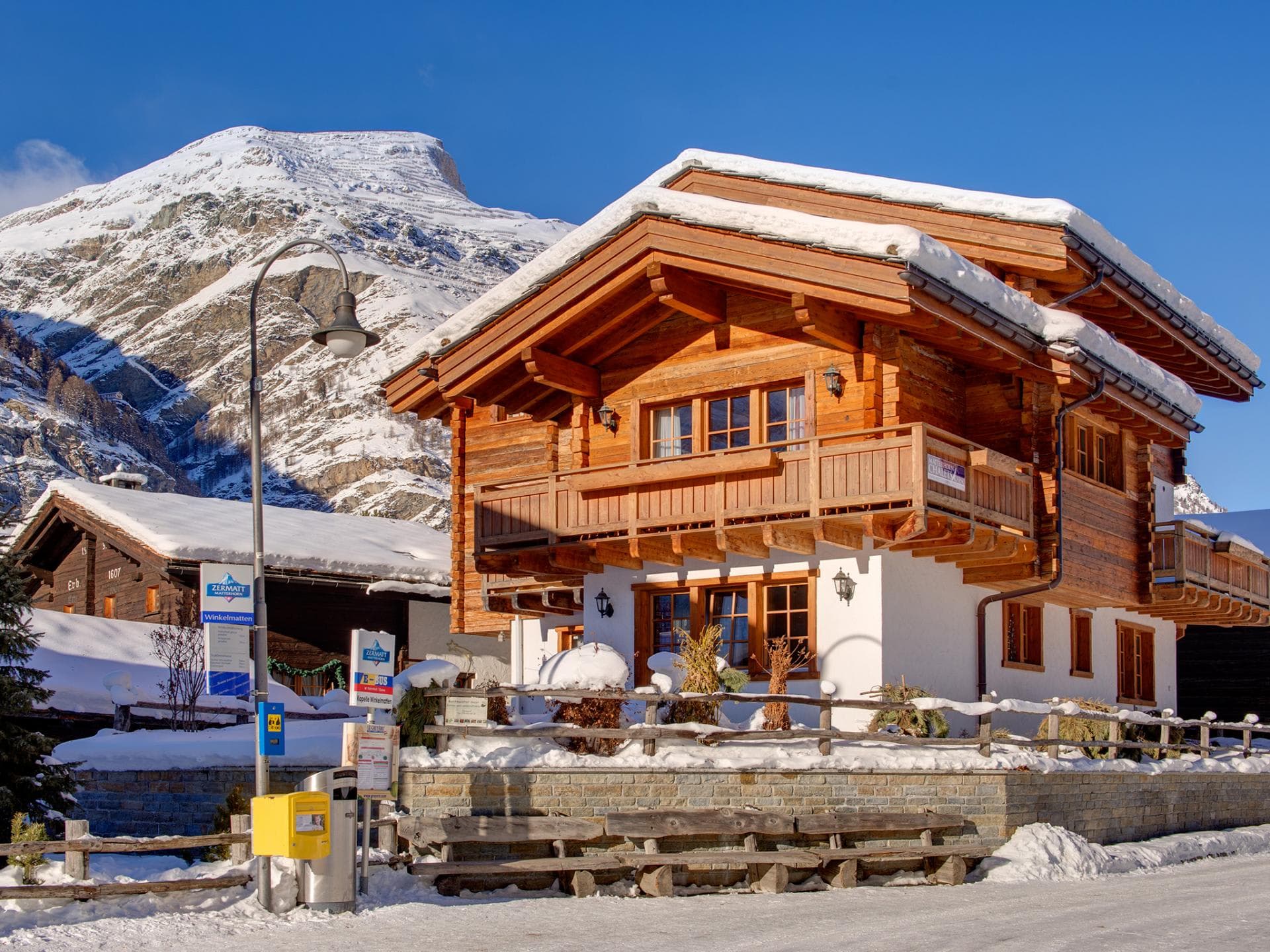 Wooden chalet exterior; ski bus stop located directly in front of property