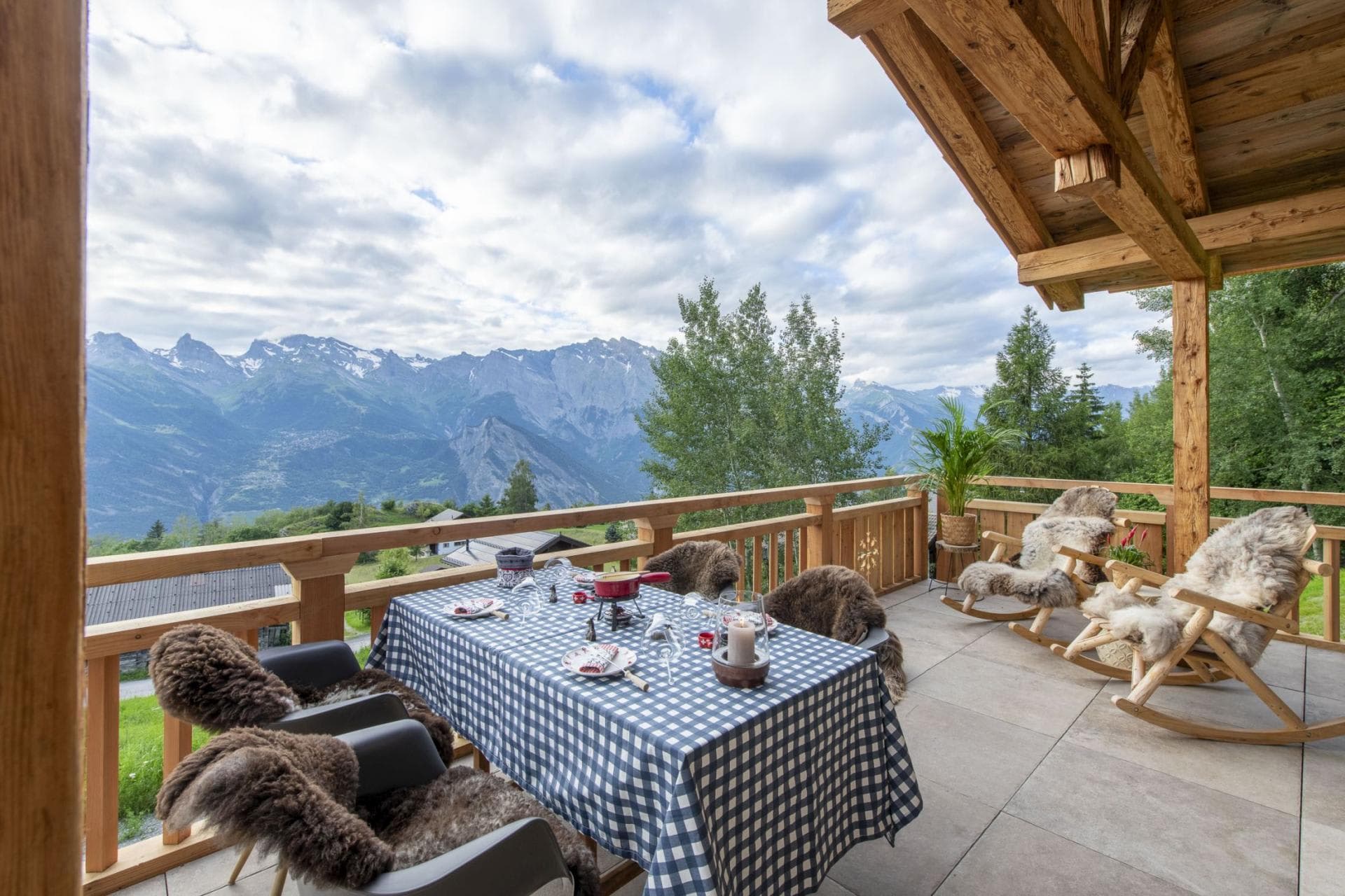 Covered terrace with dining for 4 and rocking chairs overlooking the Alps