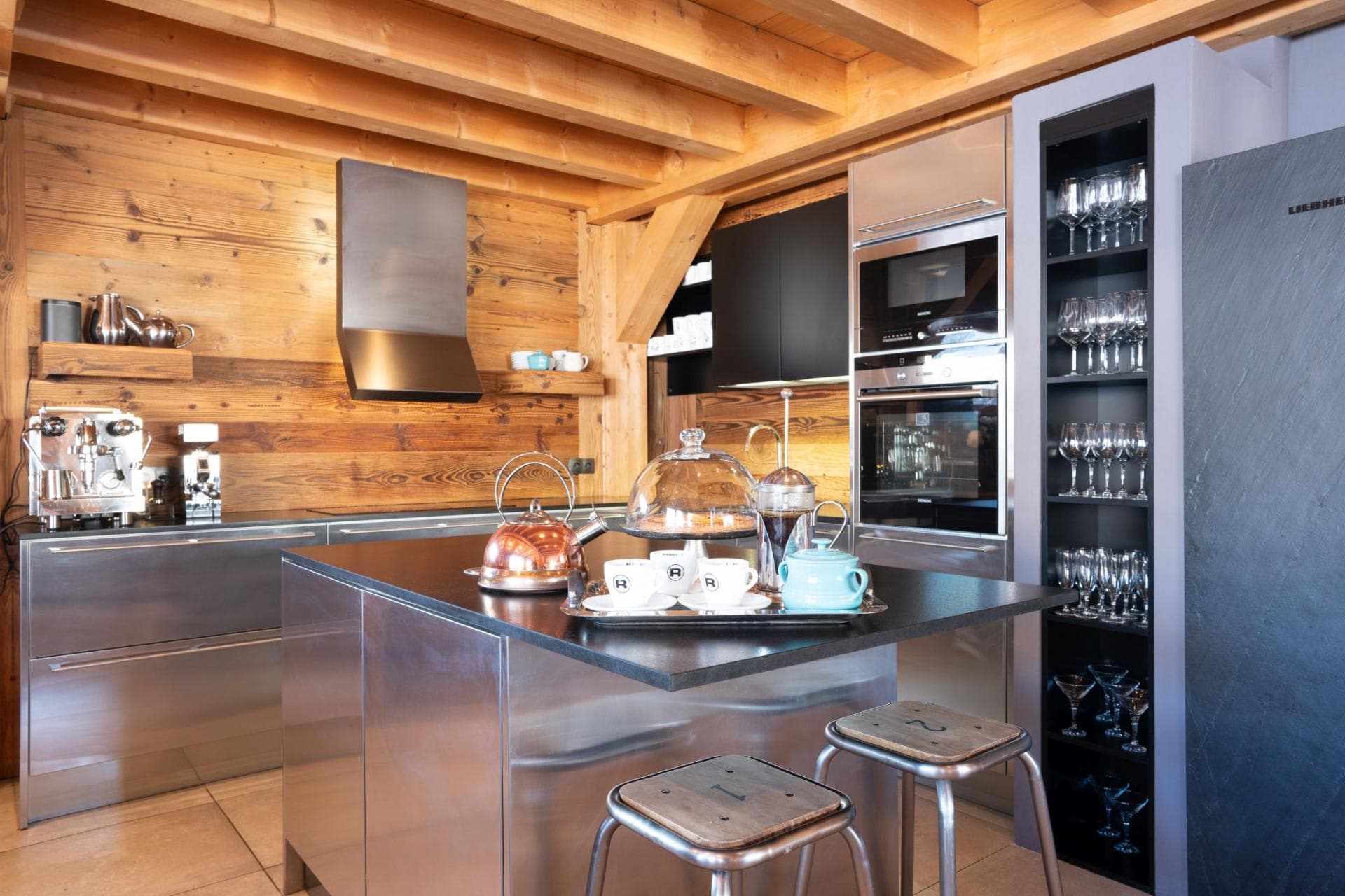 Kitchen with stainless steel island, espresso machine, and integrated wine glass storage