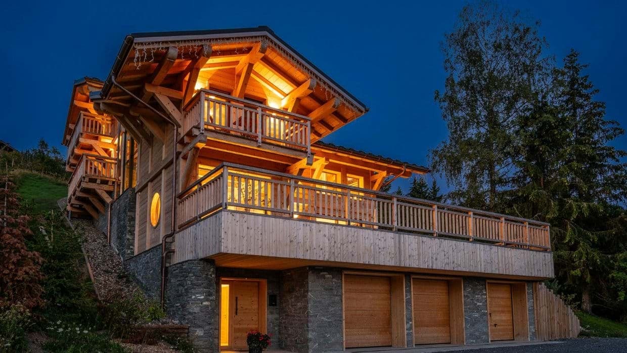 Chalet exterior with three-car garage and wraparound deck