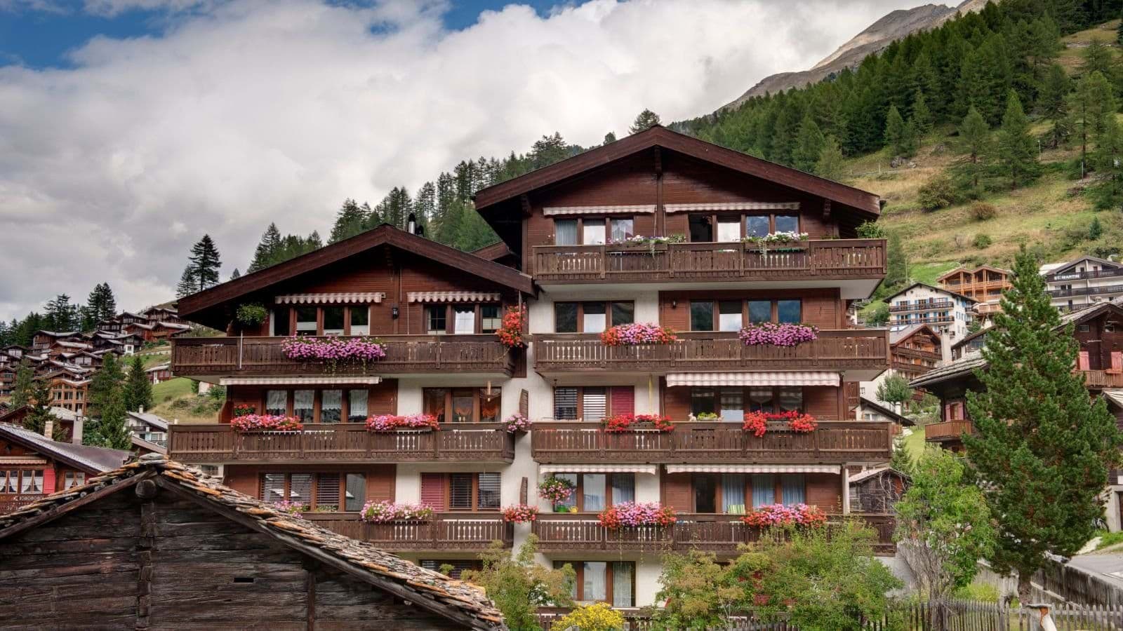 Chalet exterior featuring private balconies with flower boxes and mountain views
