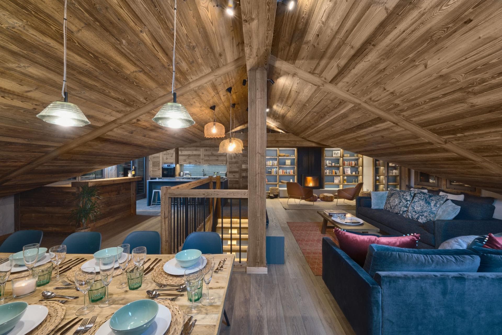Open-plan top floor with vaulted ceilings, wood paneling, and wood-burning fireplace