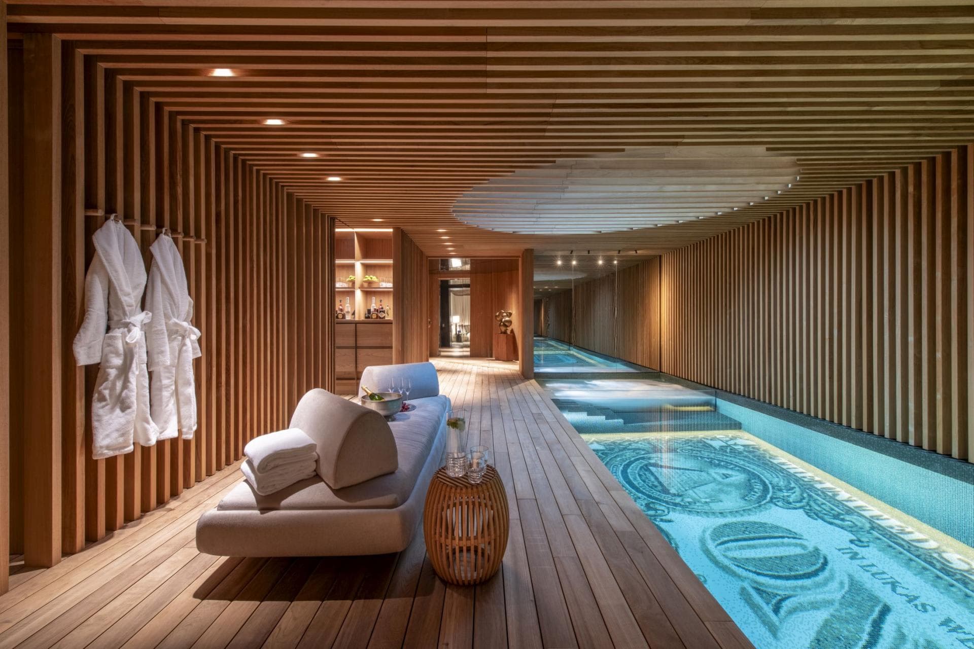 Indoor lap pool with wood-slat walls and mosaic tile flooring