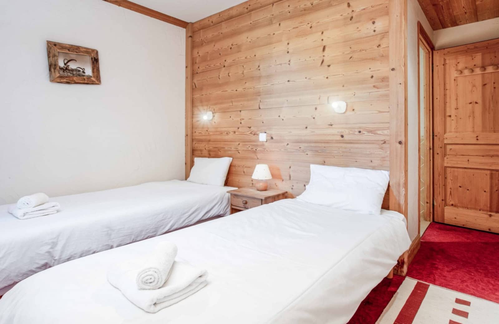 Guest bedroom with two twin beds and wood-paneled feature wall