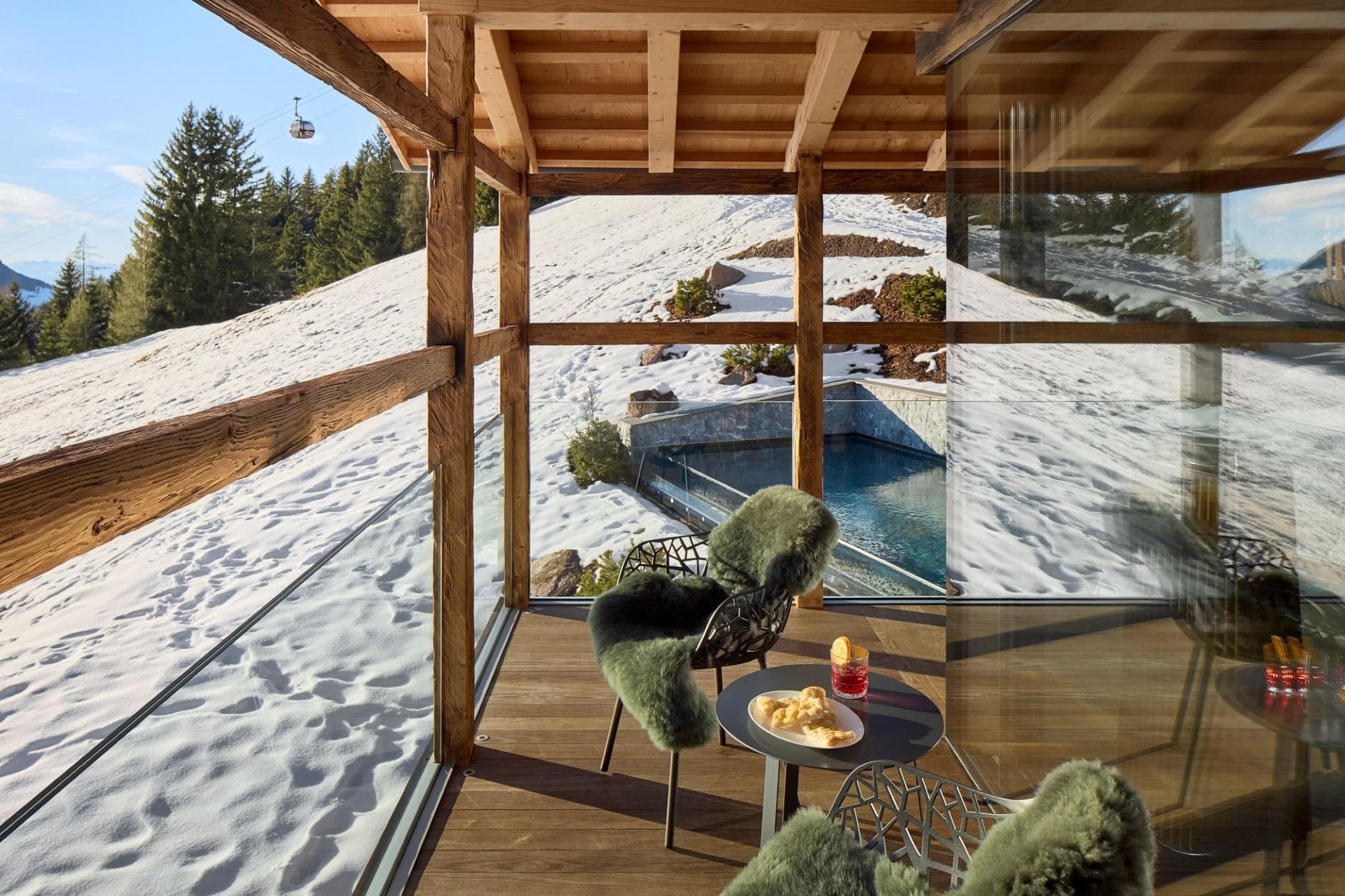 Covered terrace overlooking outdoor pool with ski gondola views