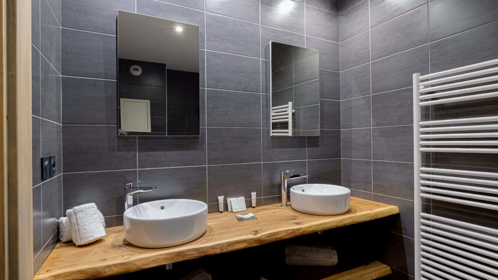 Dual vessel sinks on live-edge wood vanity with heated towel rack