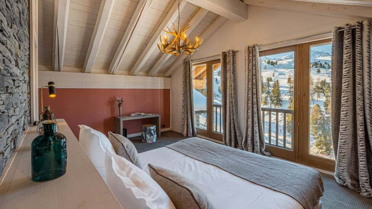 Bedroom with vaulted timber ceiling and direct ski slope views
