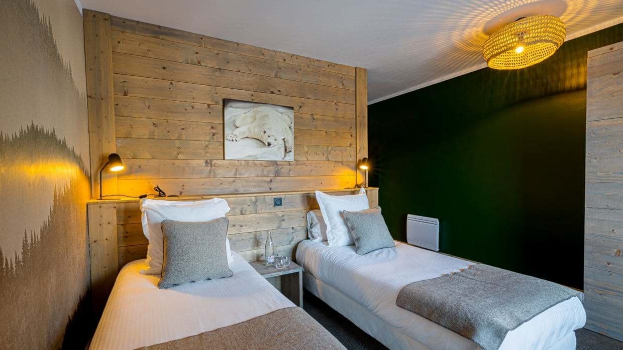 Twin bedroom with individual reading lamps and wood-paneled wall