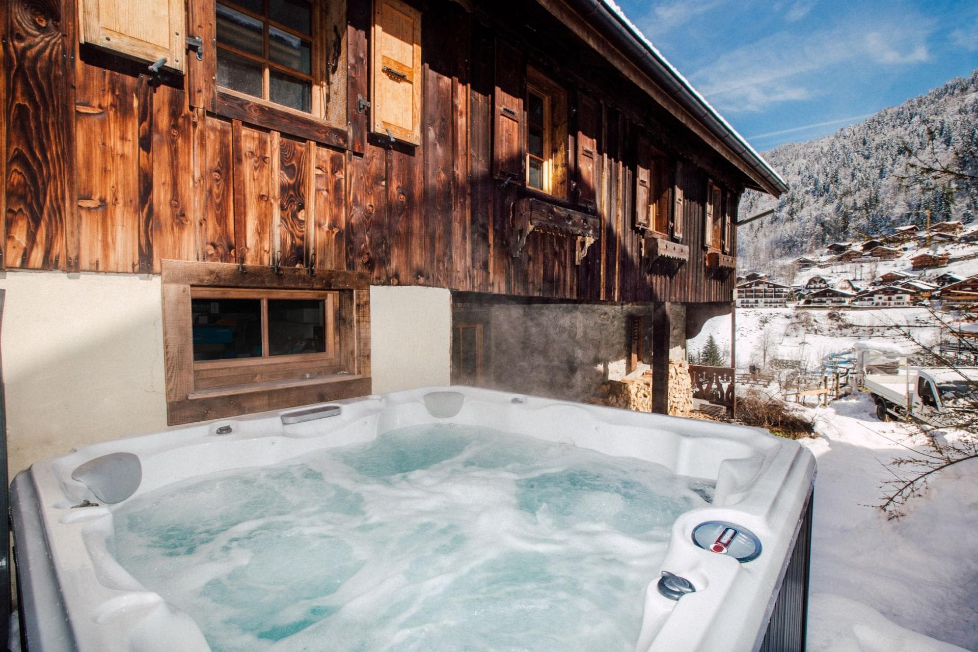 Outdoor hot tub with mountain views beside a traditional timber chalet