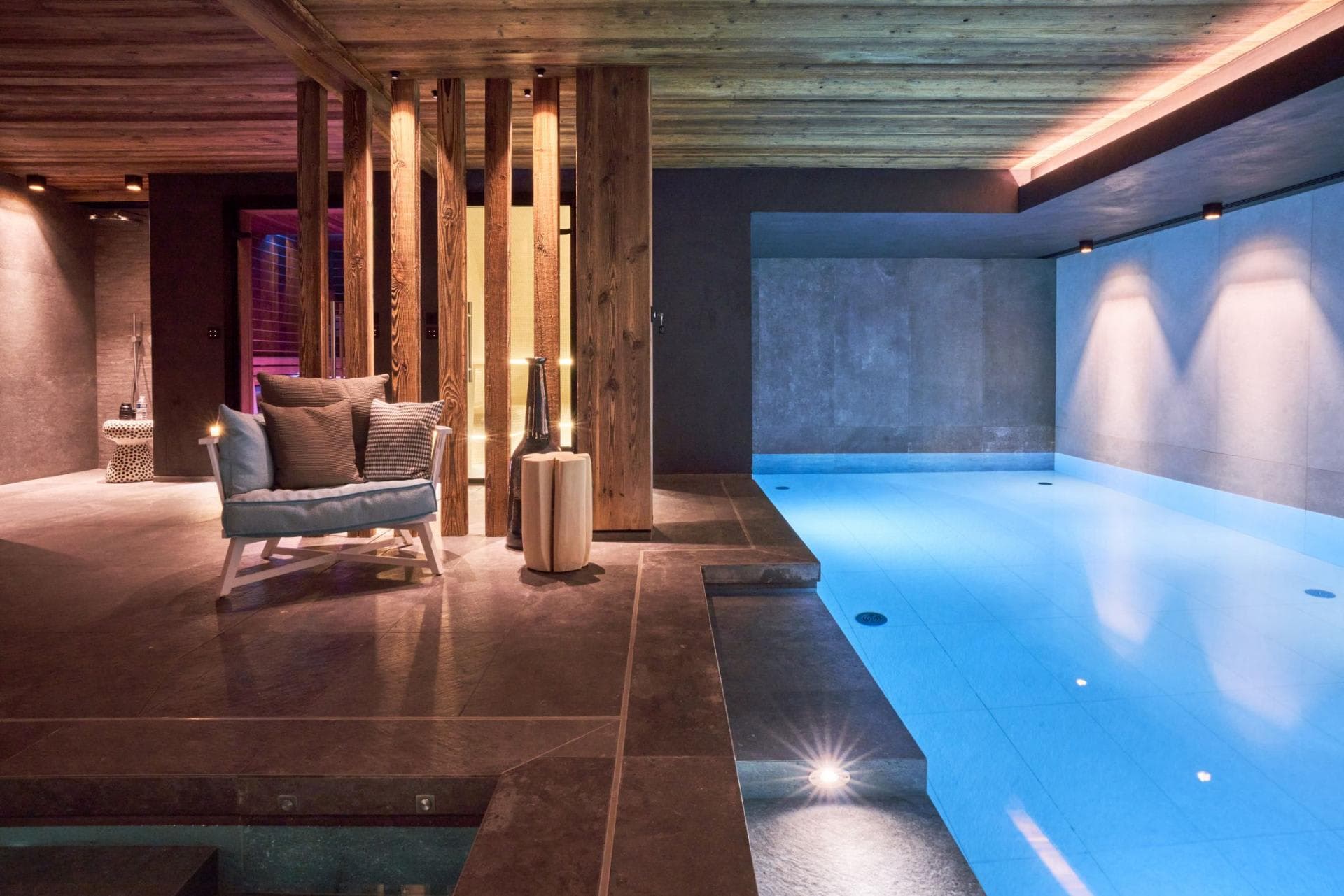 Indoor heated pool with lounge seating and adjacent walk-in shower