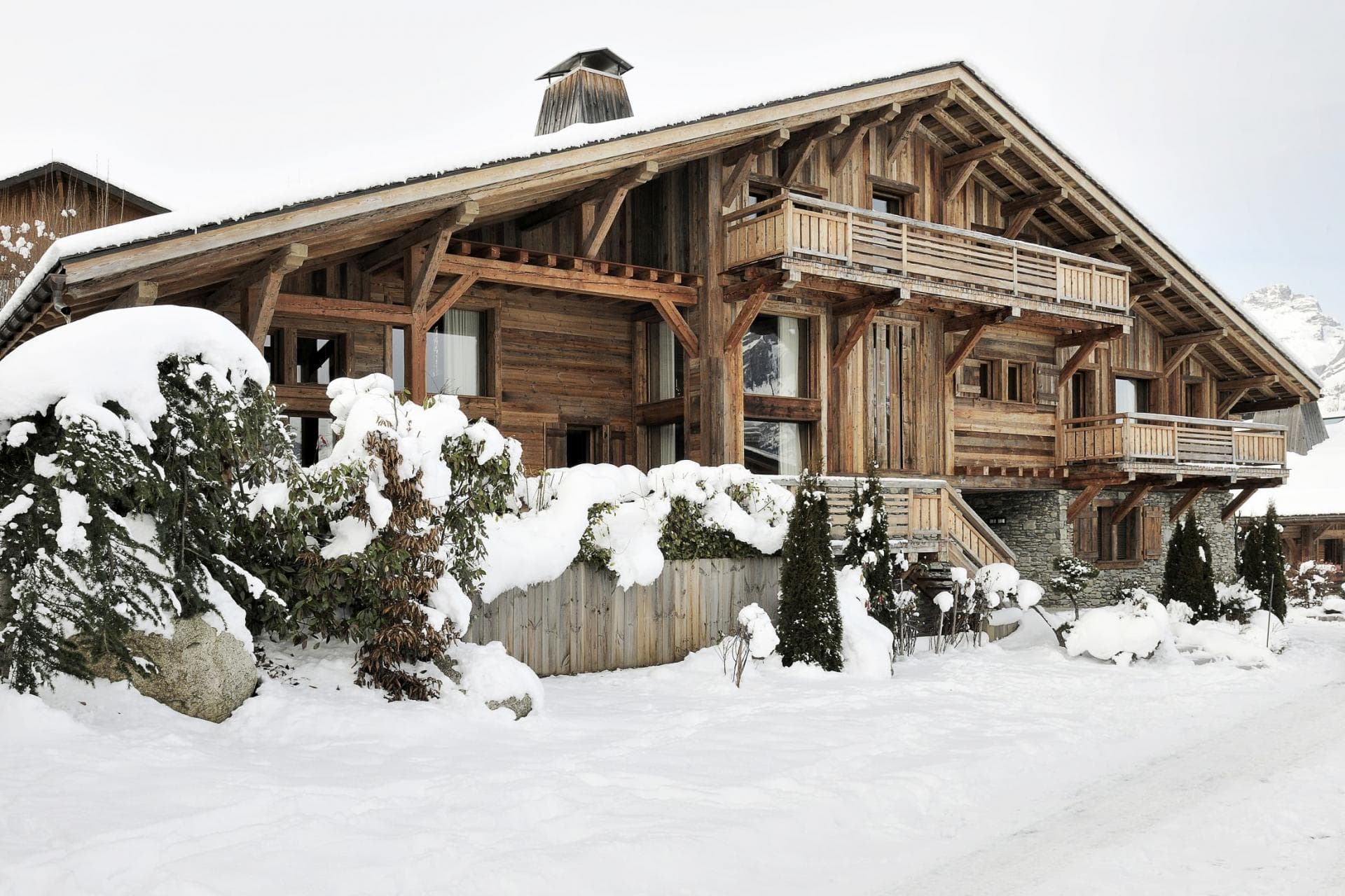 Timber chalet exterior featuring private balconies and stone-foundation ground level