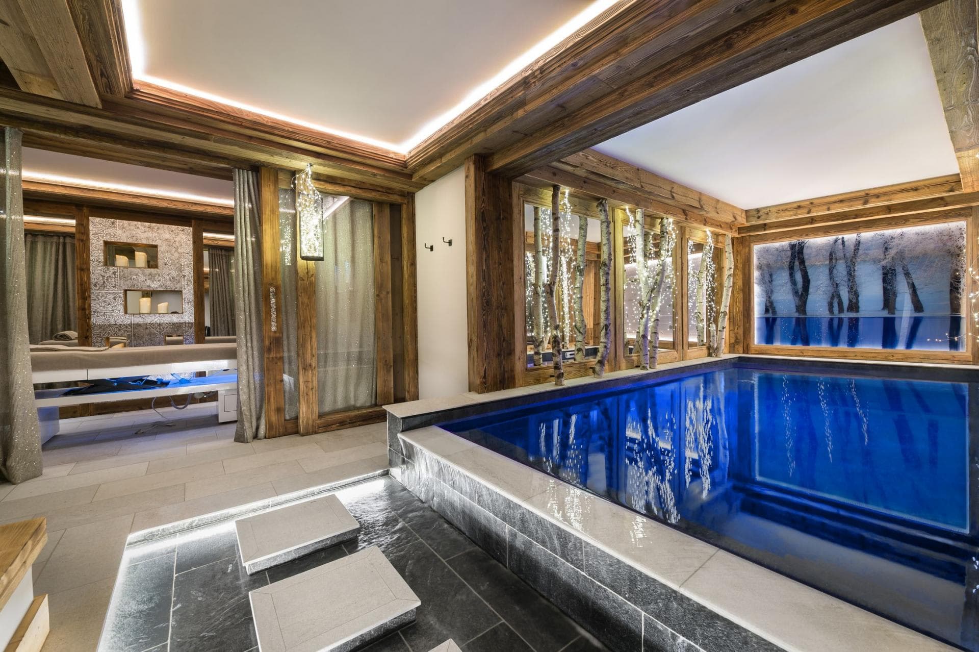 Indoor heated pool and spa area with adjacent massage treatment room