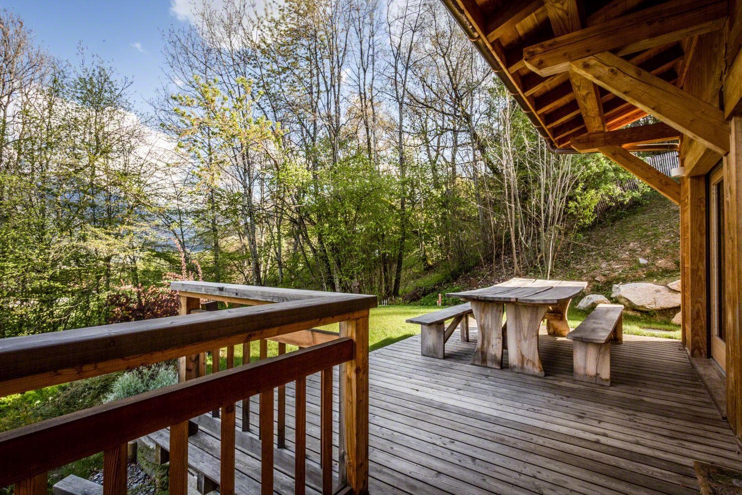 Covered deck with stone picnic table and seating; forest and hillside views