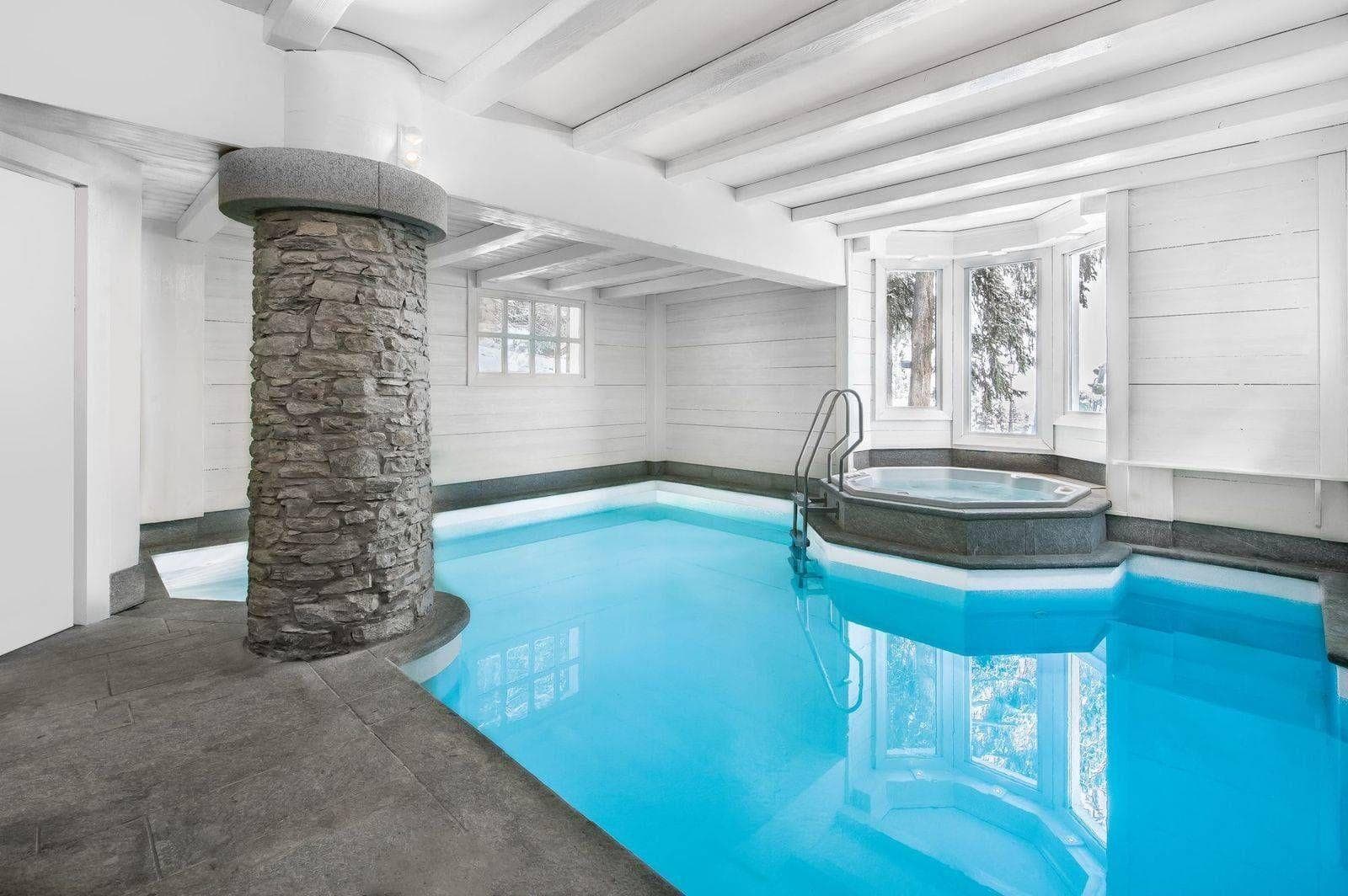 Indoor heated pool and integrated hot tub with stone pillar accents