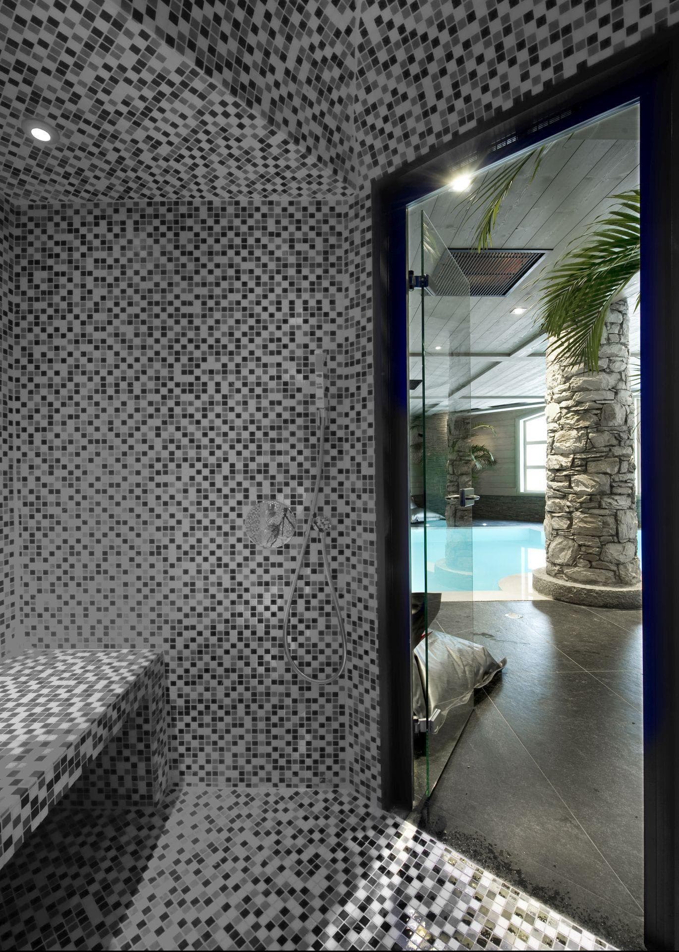 Mosaic-tiled steam room with bench seating and view of indoor pool