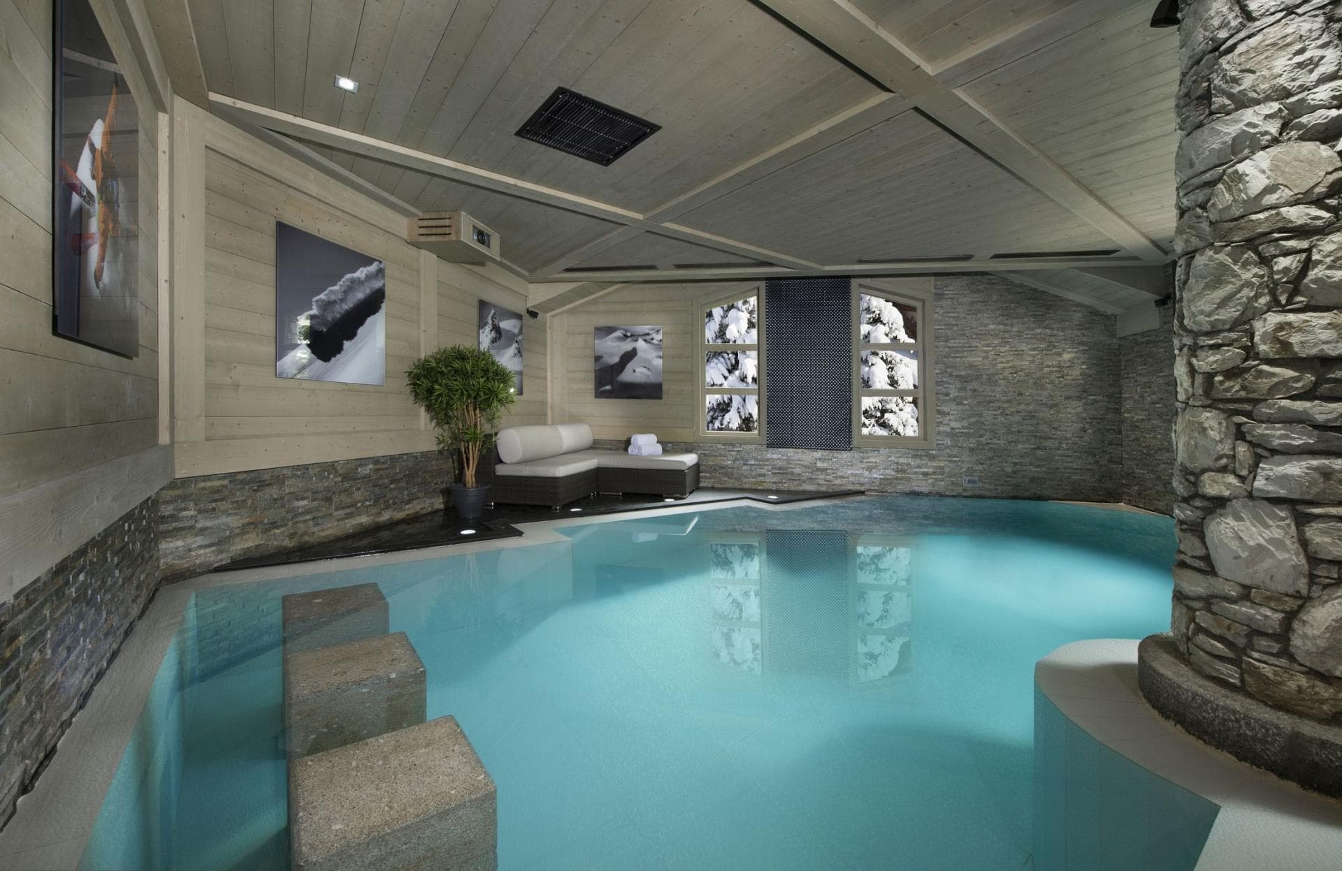 Indoor heated pool with swim-up bar stools and snowy forest views