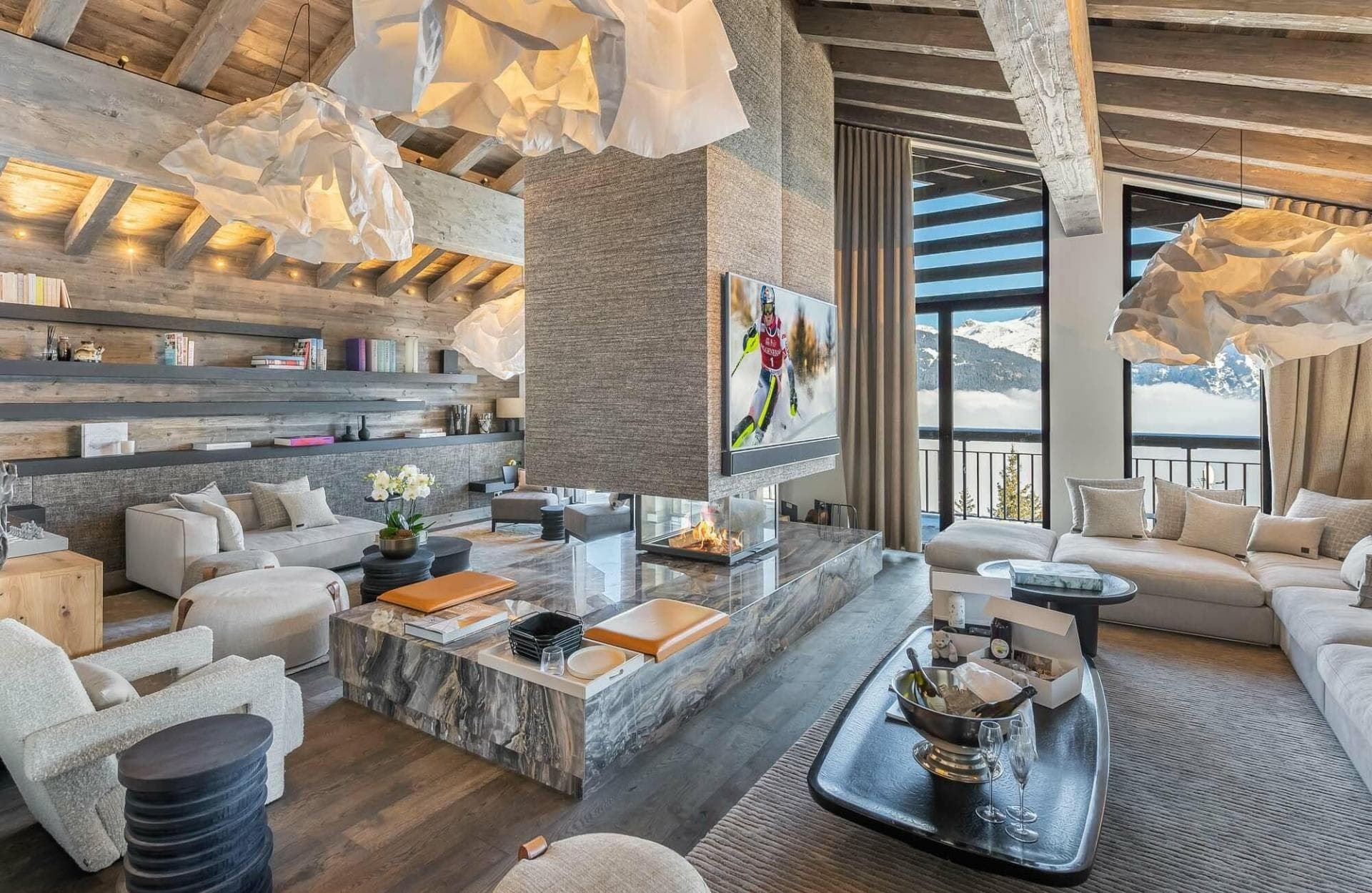 Living area with a central glass fireplace and mountain views