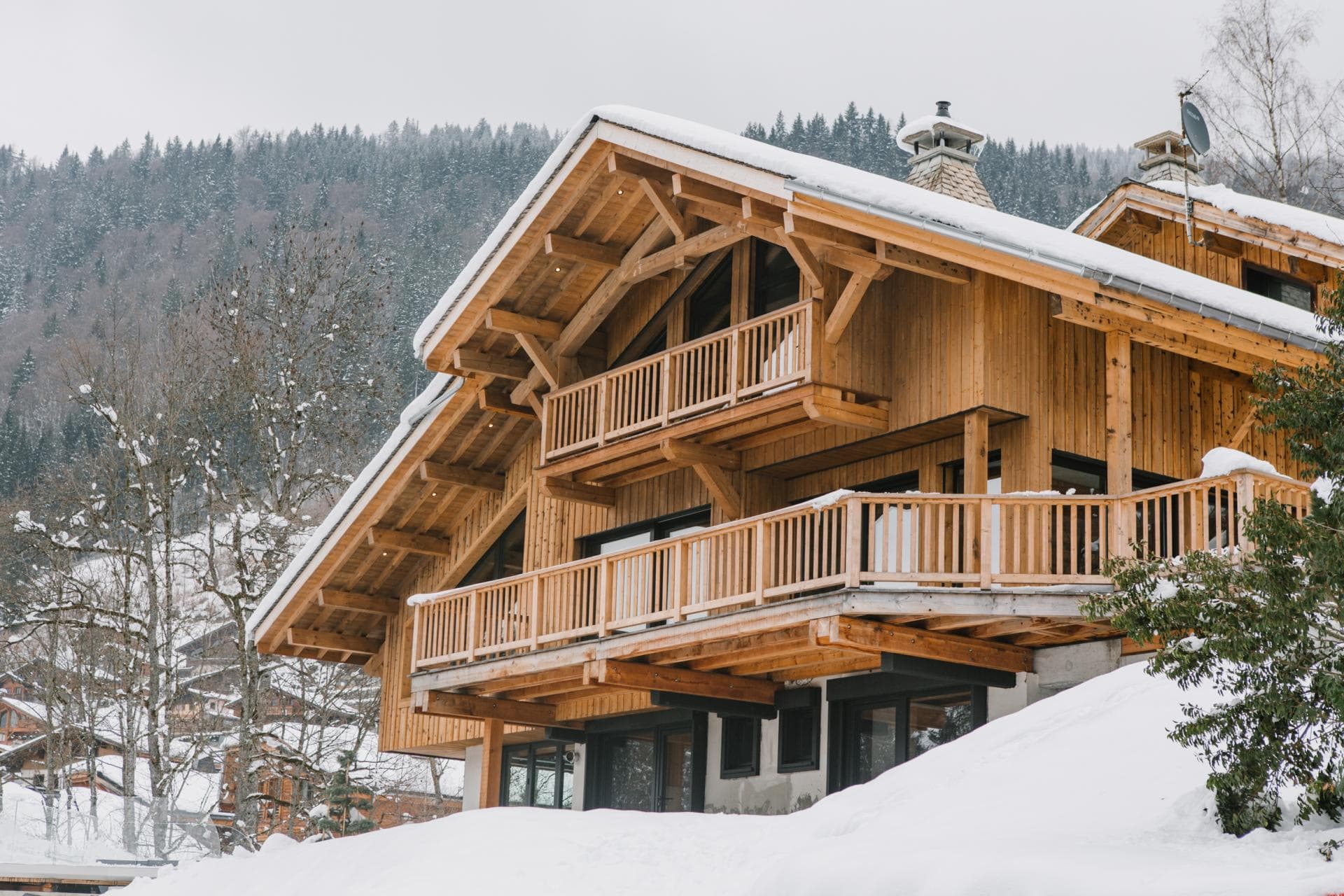 Timber chalet exterior with multi-level balconies and mountain forest backdrop