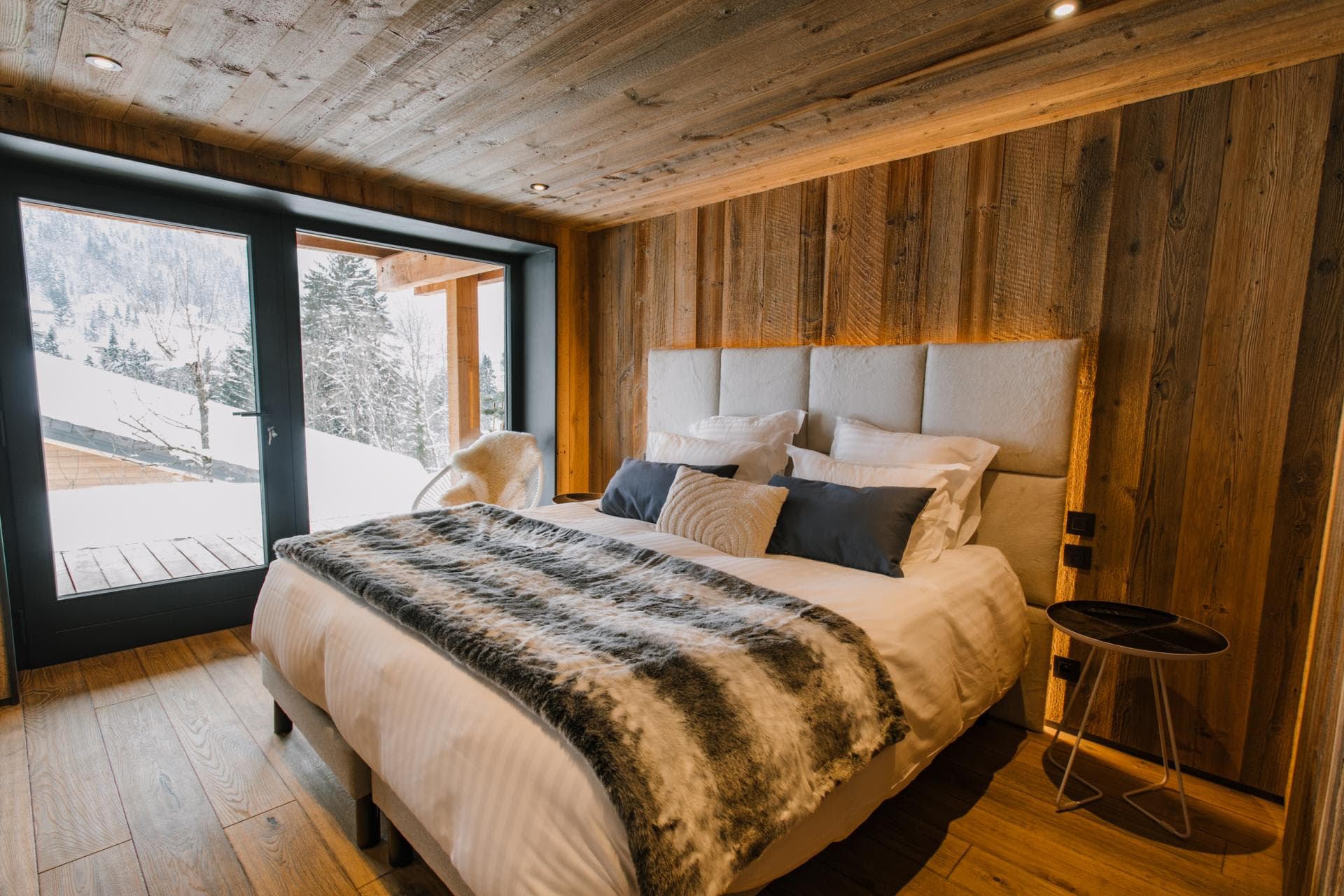 King bedroom with wood-paneled walls and private terrace access