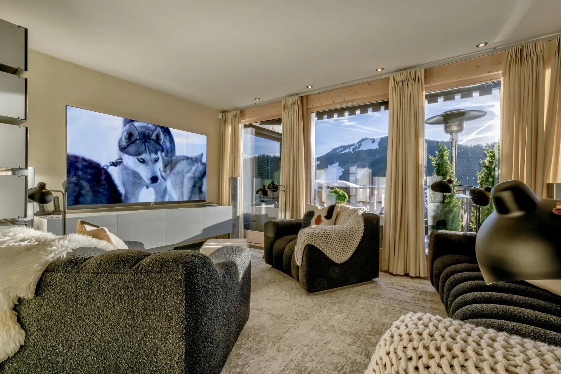 Living area with large-screen TV and floor-to-ceiling mountain views