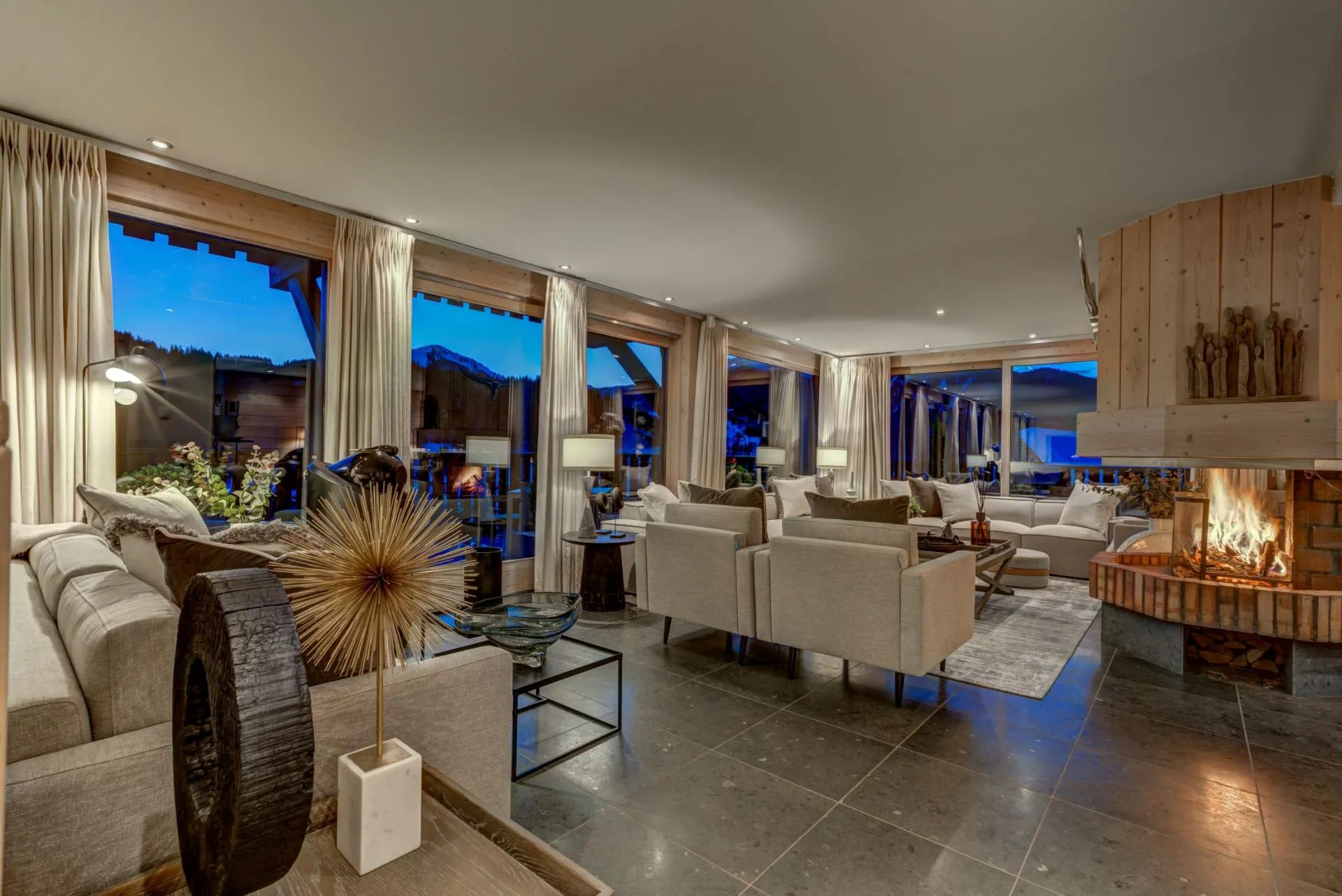 Living room with wood-burning fireplace and floor-to-ceiling mountain views