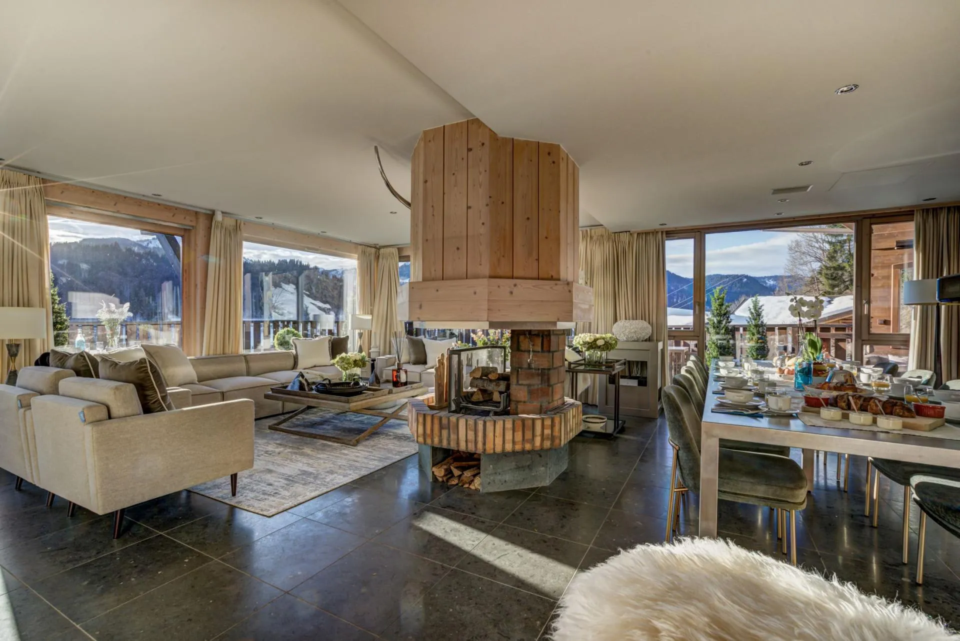 Living and dining area with central wood-burning fireplace and mountain views