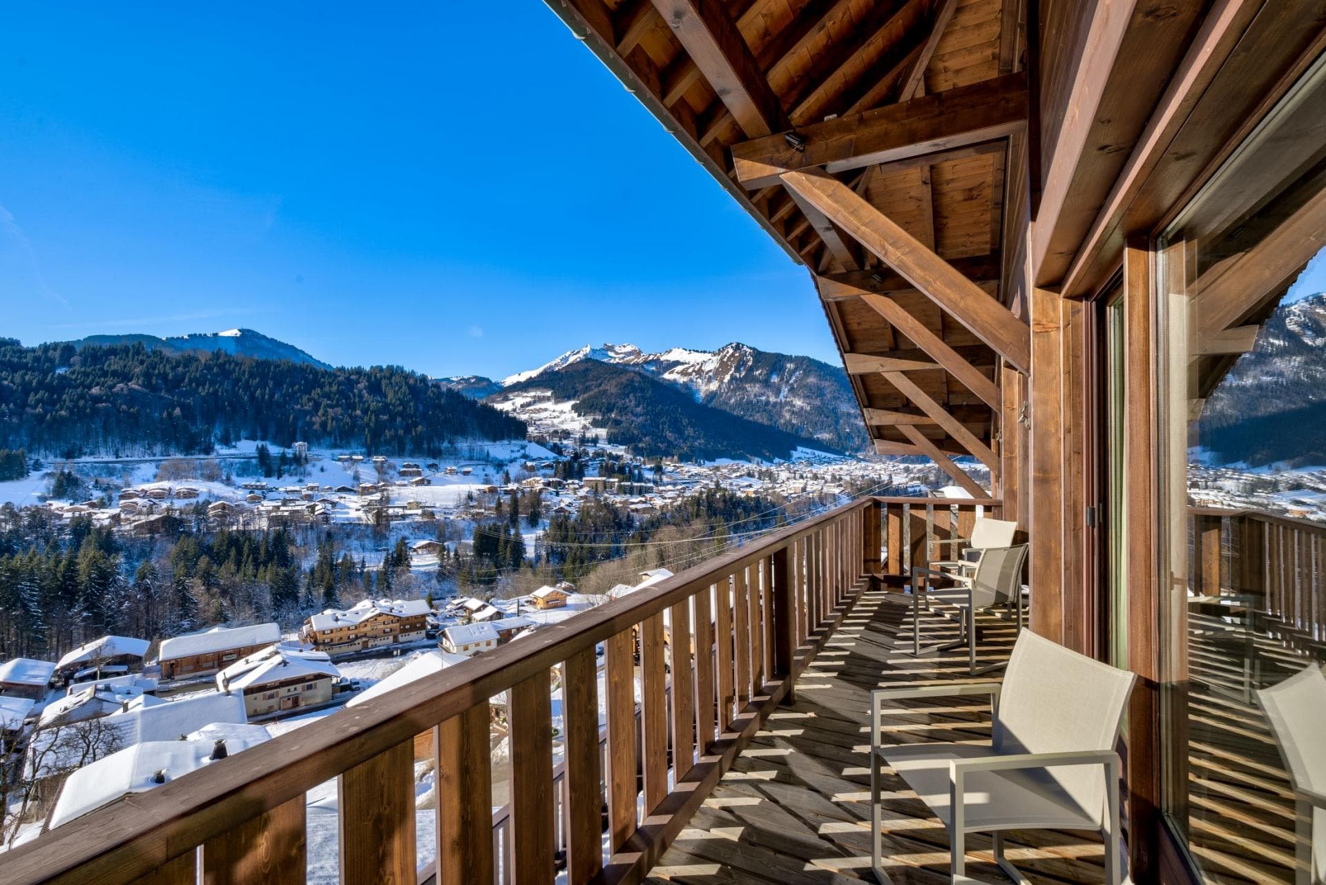 Covered wooden balcony with seating; village and mountain views