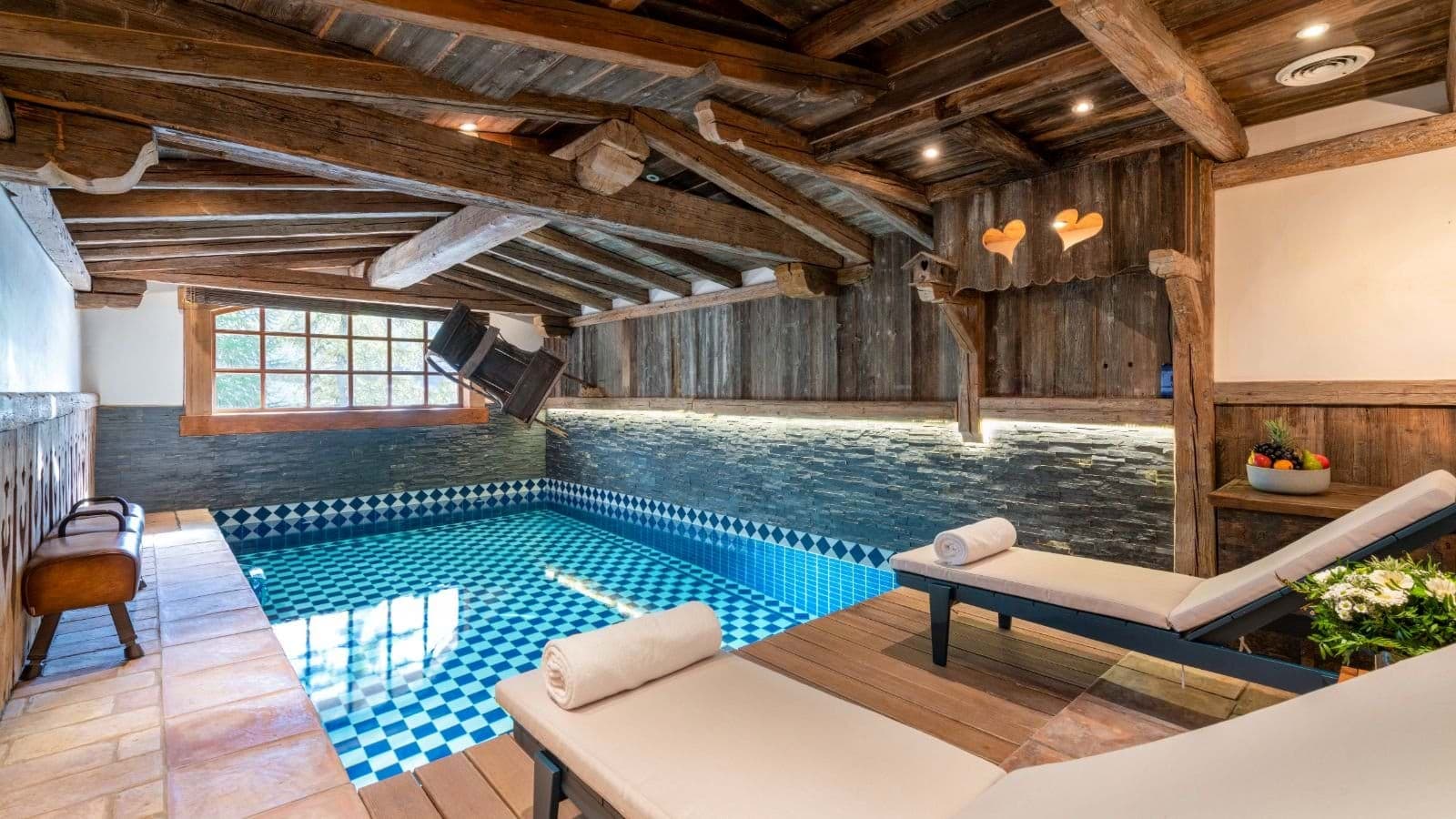Indoor heated pool with timber beams and poolside lounge seating