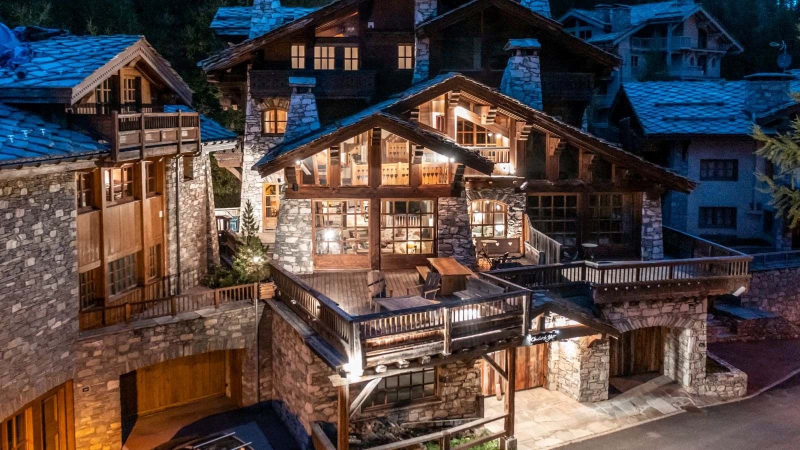 Chalet exterior at dusk with wrap-around deck and heated outdoor seating