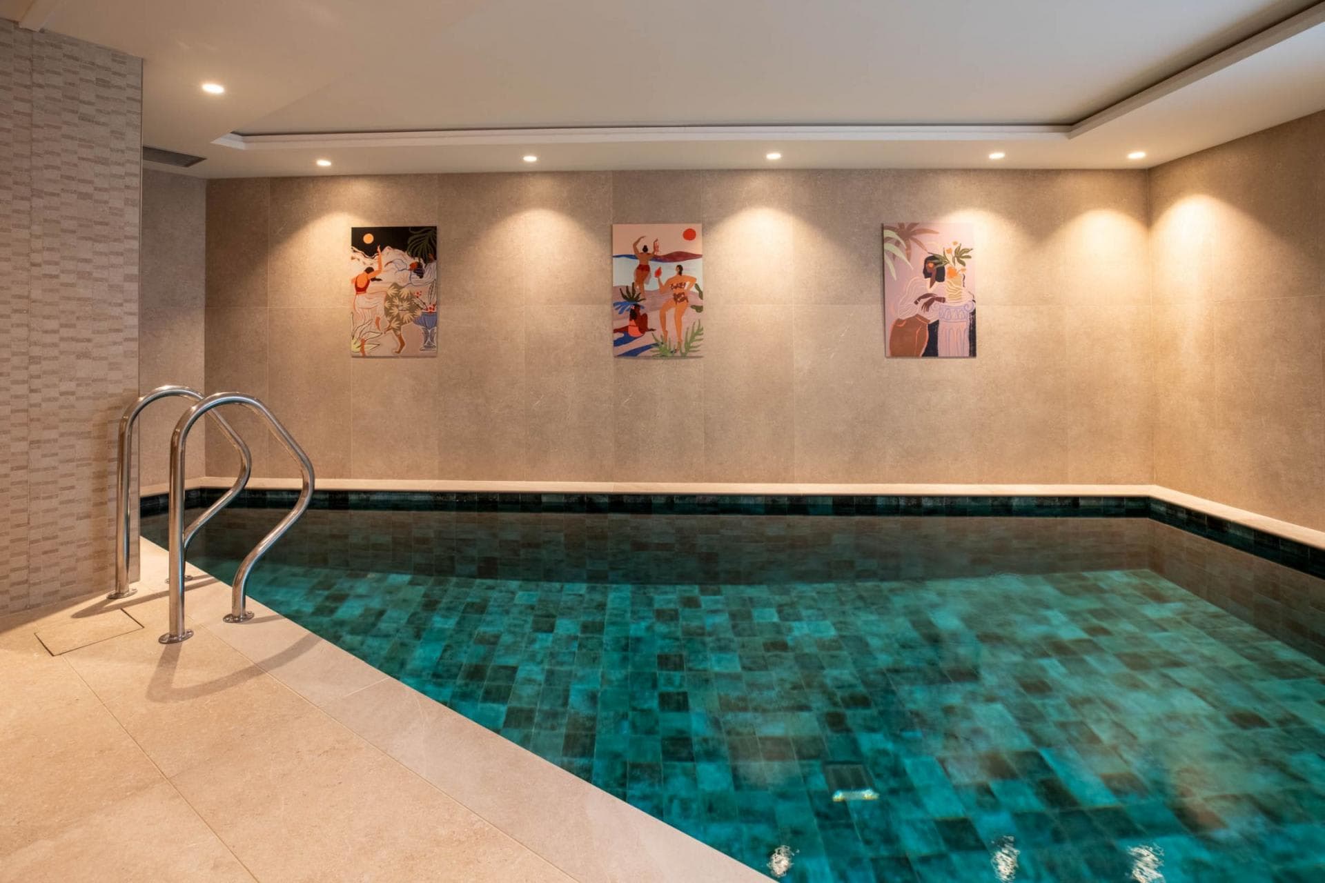 Indoor heated pool with handrail and emerald green mosaic tiling