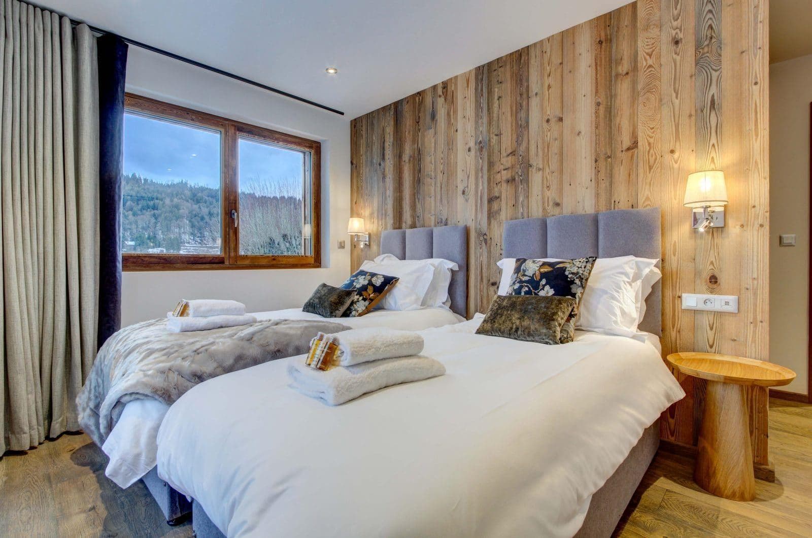 Bedroom with twin beds and wood paneling; forest views