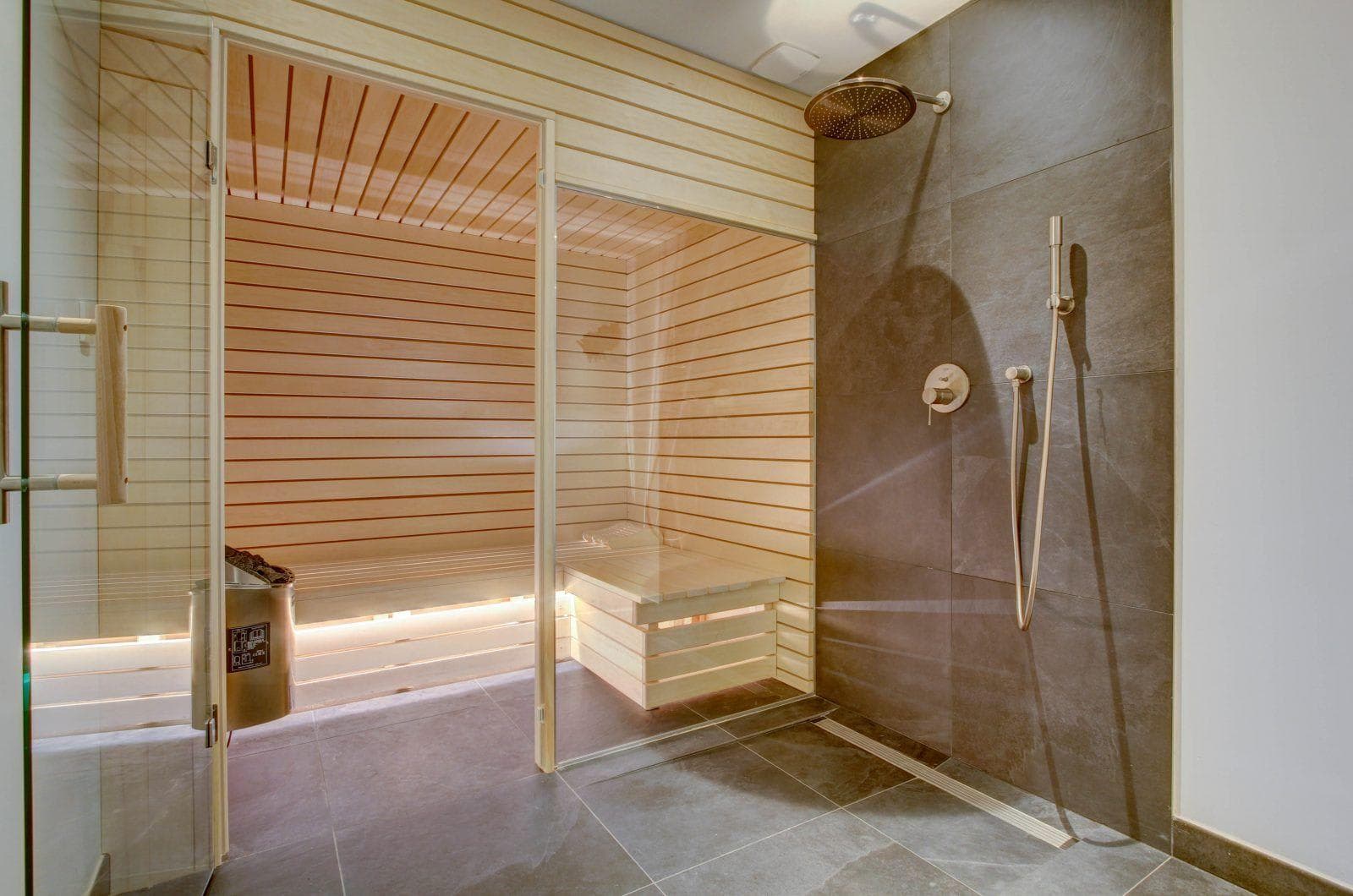 Wood-paneled sauna and walk-in shower with rain head and handheld sprayer