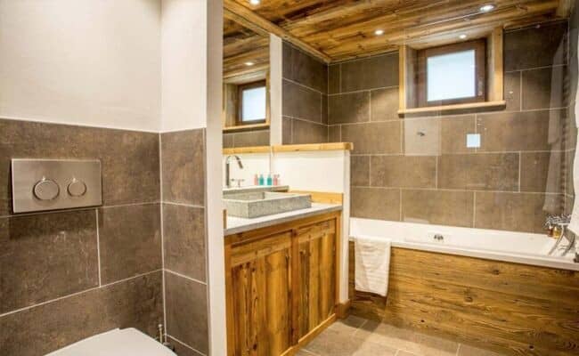 Bathroom with wood-paneled bathtub and stone vessel sink