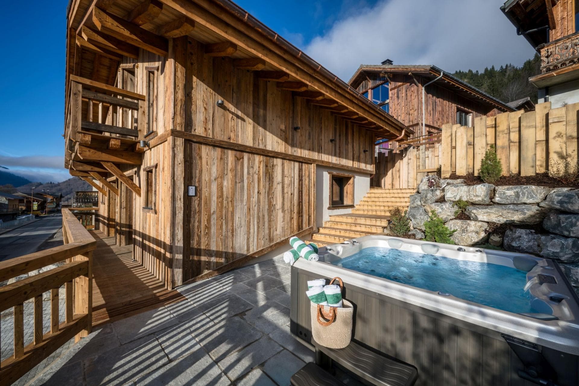 Outdoor hot tub on private stone patio with wooden chalet backdrop