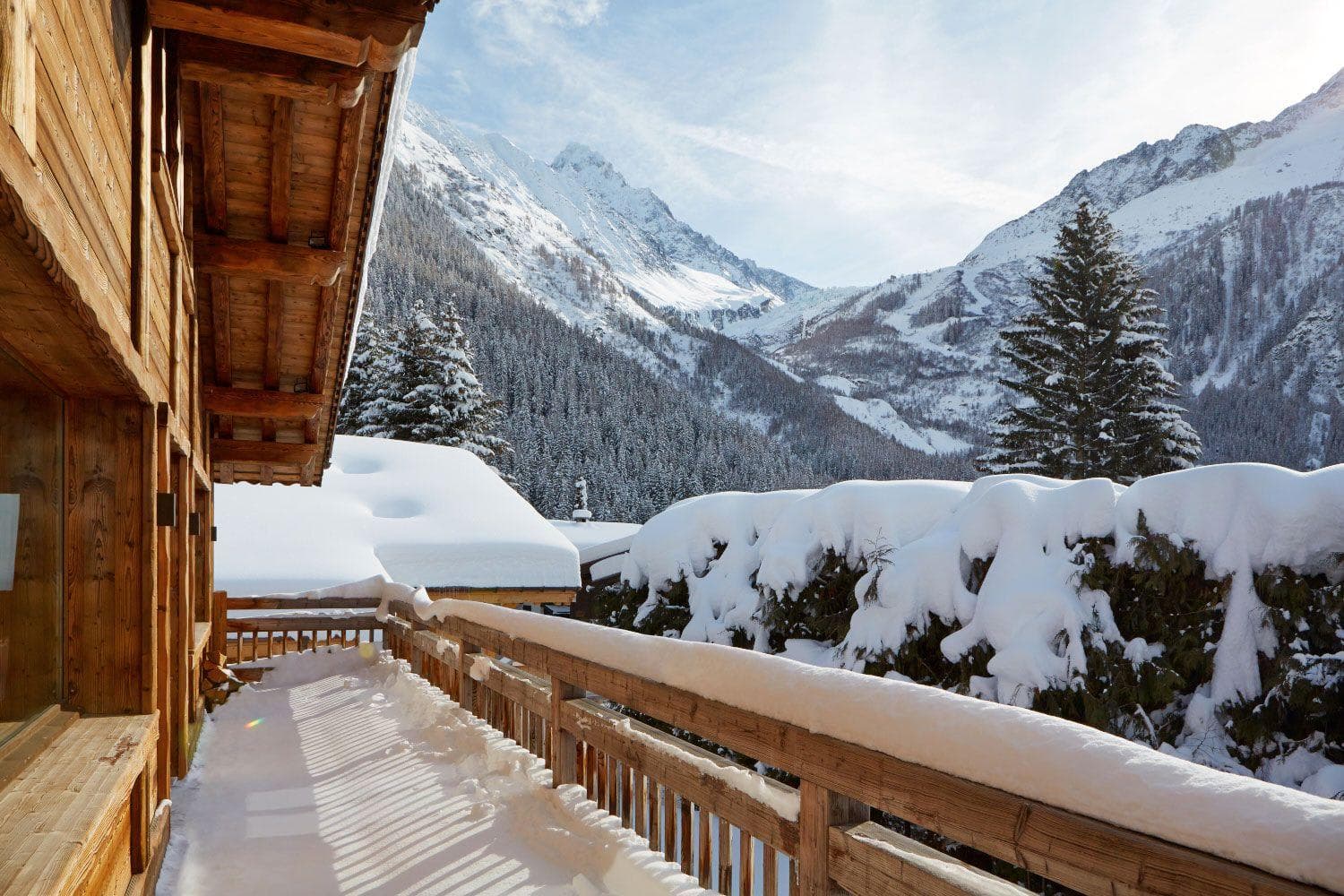 Covered wooden balcony with views of snow-covered pine forest and mountains