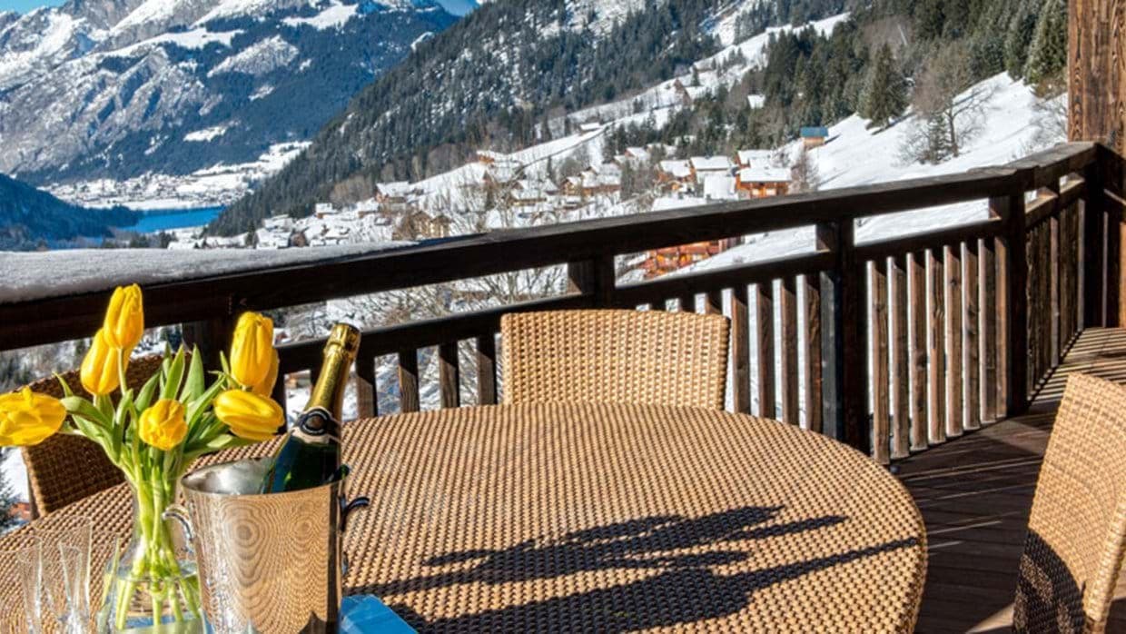 Private balcony with woven dining set and mountain valley views