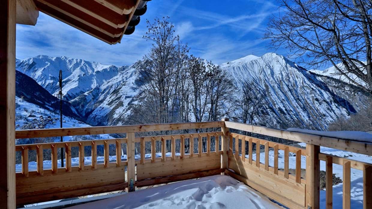 Wooden balcony with panoramic mountain views and valley village below