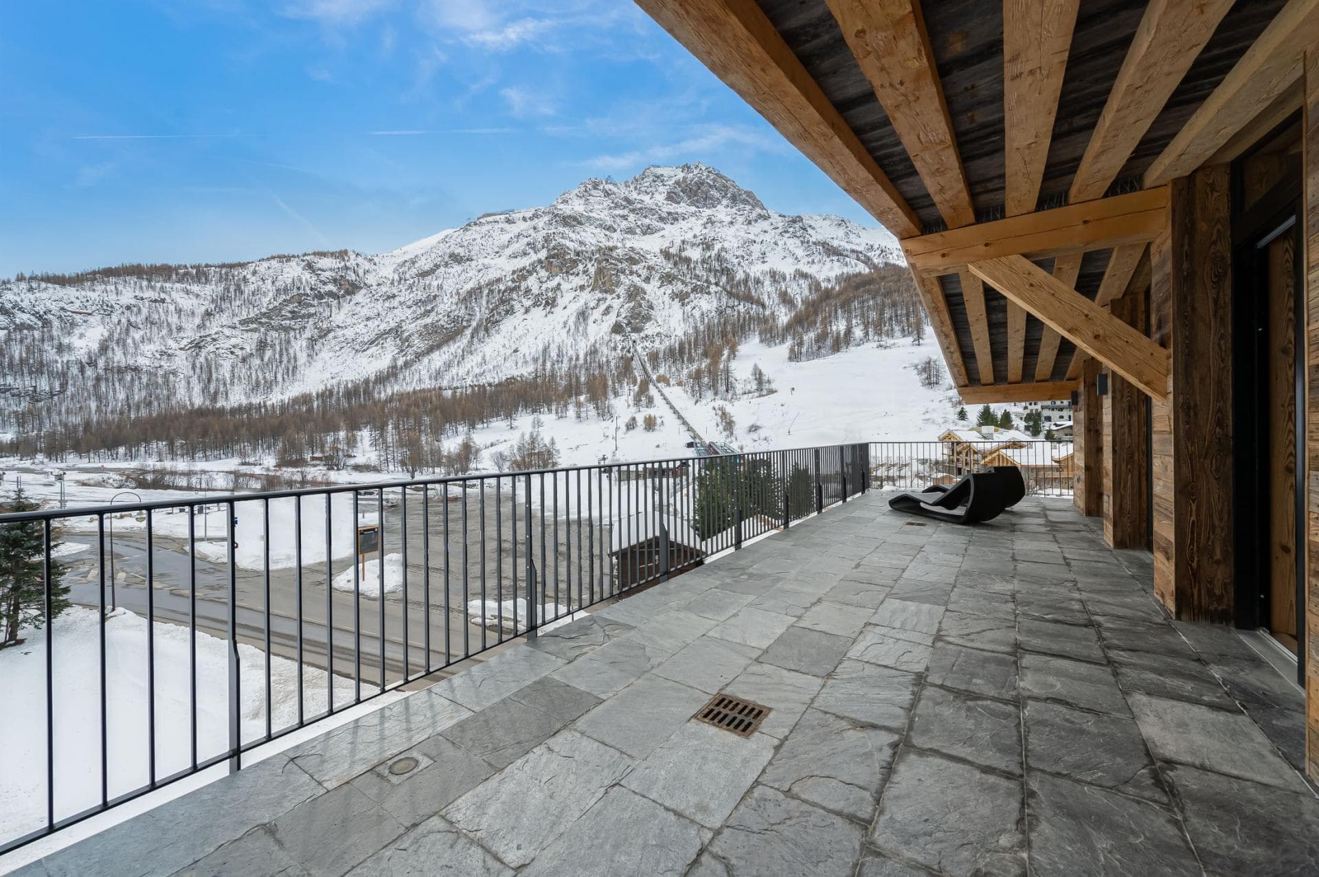 Stone-tiled balcony with loungers and mountain views near ski lift