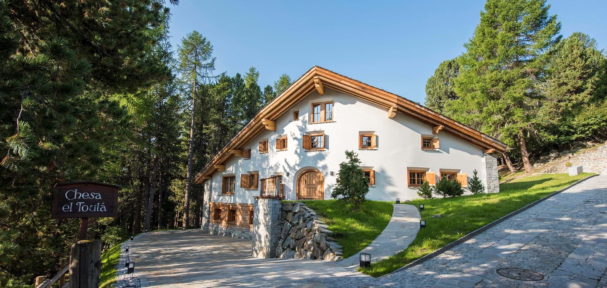 Chalet entrance with private stone driveway and surrounding pine forest