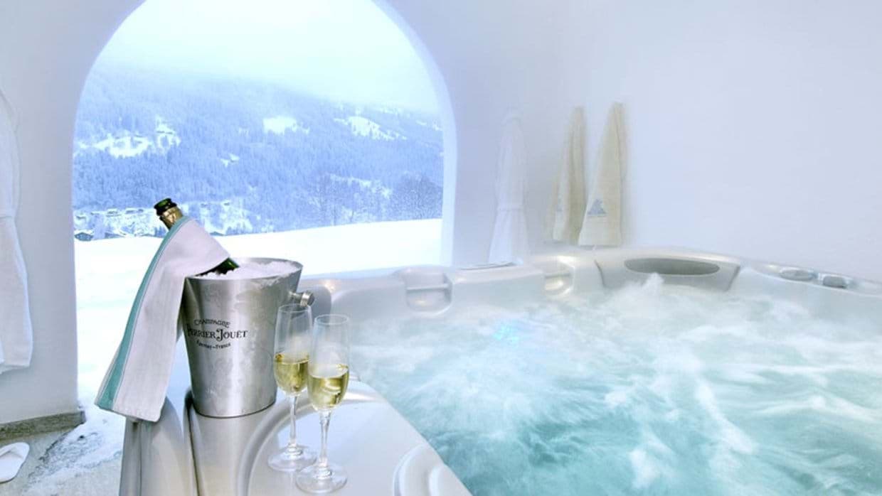 Indoor hot tub with arched window overlooking snowy mountain valley
