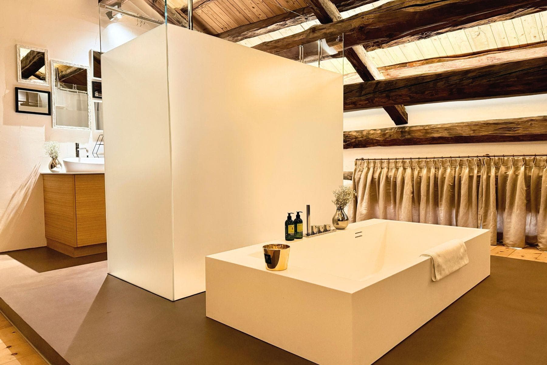 Bathroom featuring soaking tub and frosted glass shower beneath original timber beams