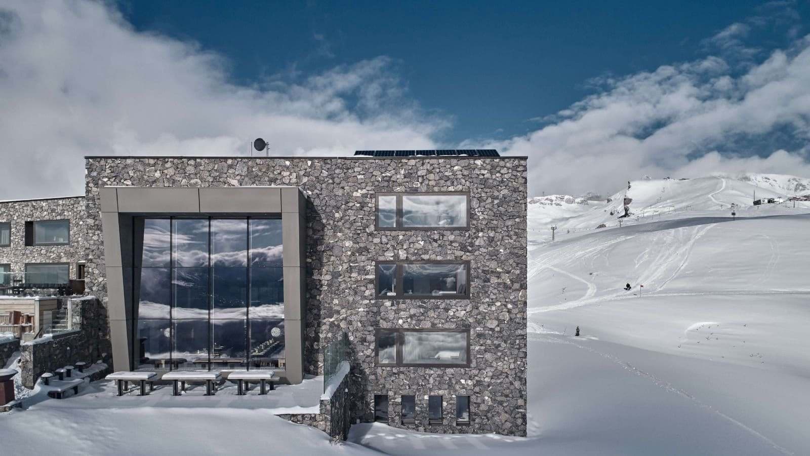 Stone chalet featuring direct ski-in/ski-out access and roof-mounted solar panels