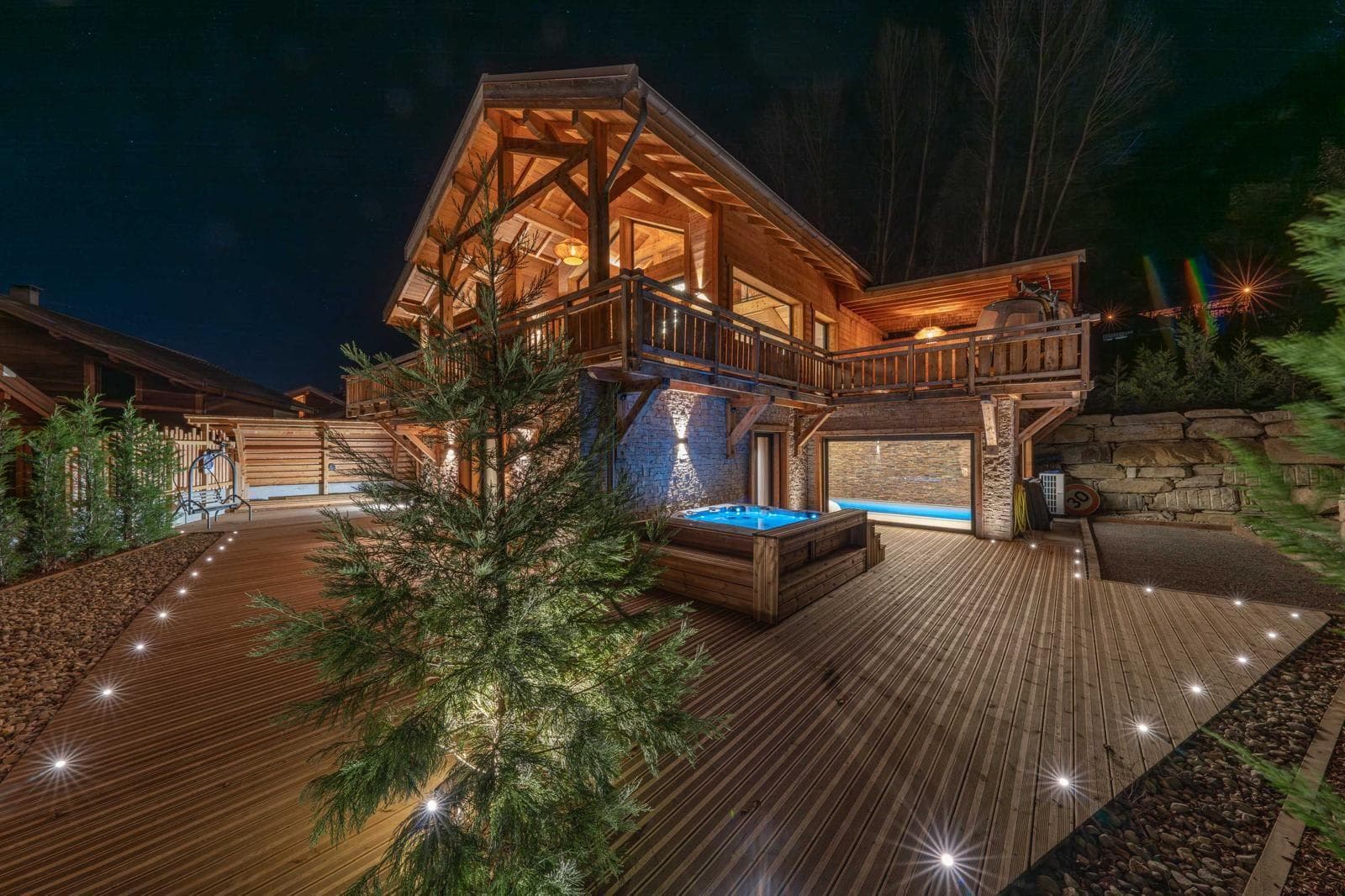 Chalet exterior with illuminated deck, hot tub, and heated indoor pool