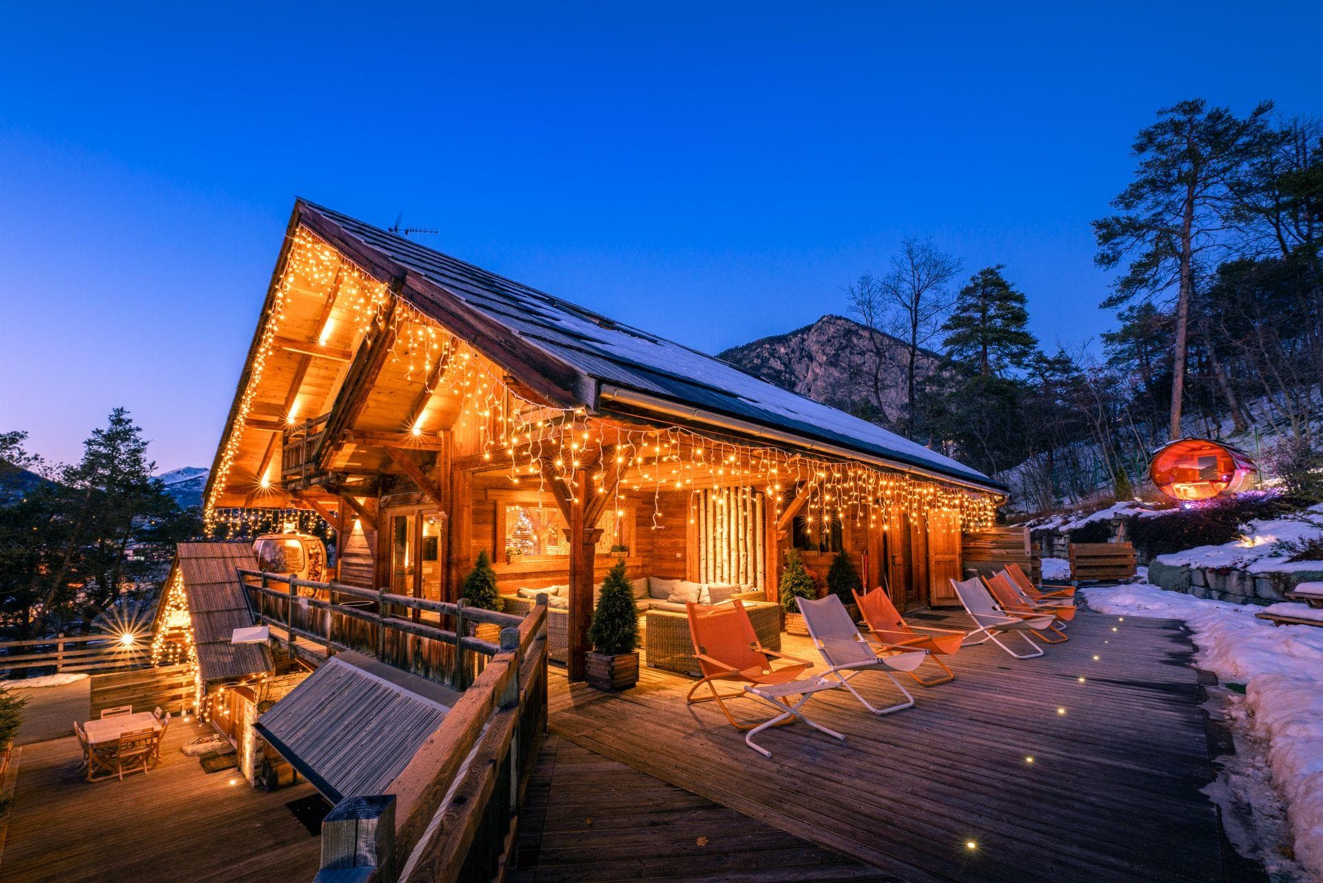 Chalet deck with lounge seating and barrel sauna overlooking the mountains