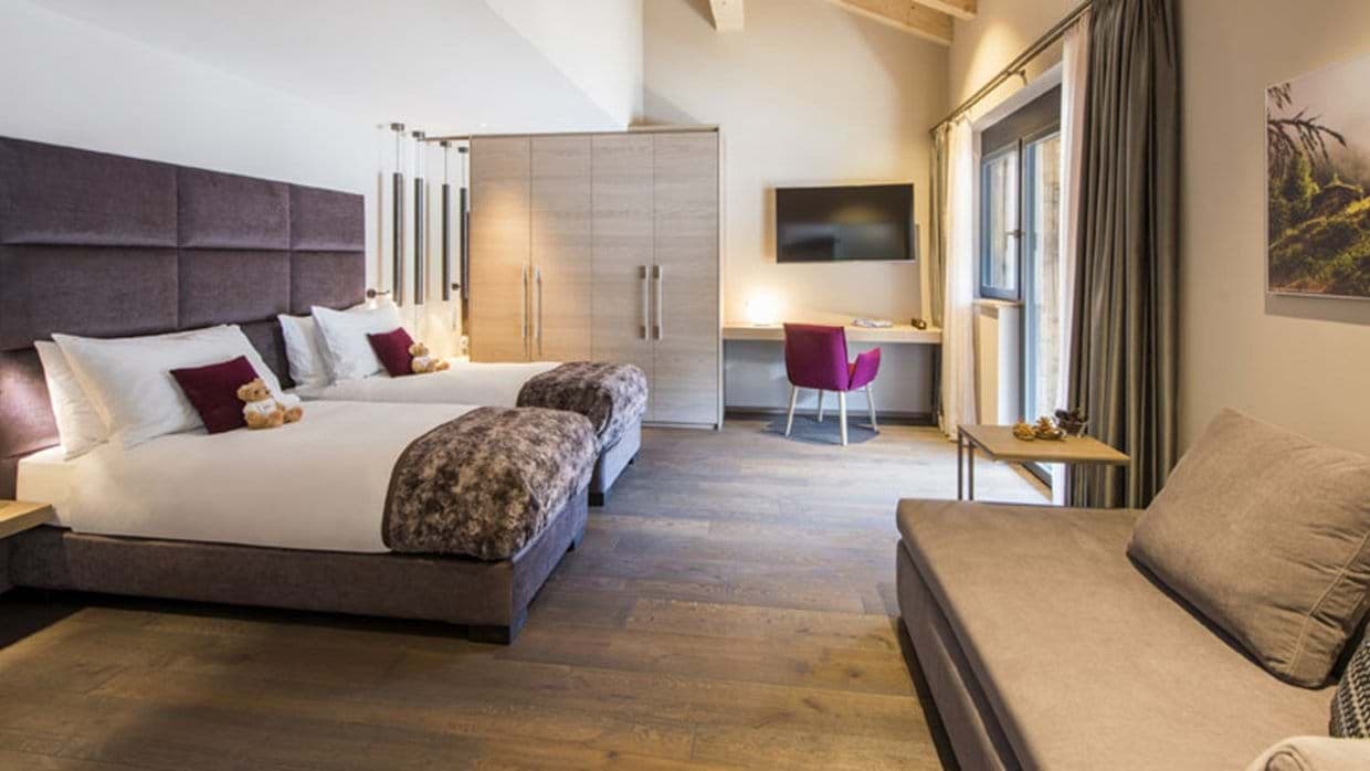 Bedroom with two queen beds, purple headboard, desk workspace, and balcony access