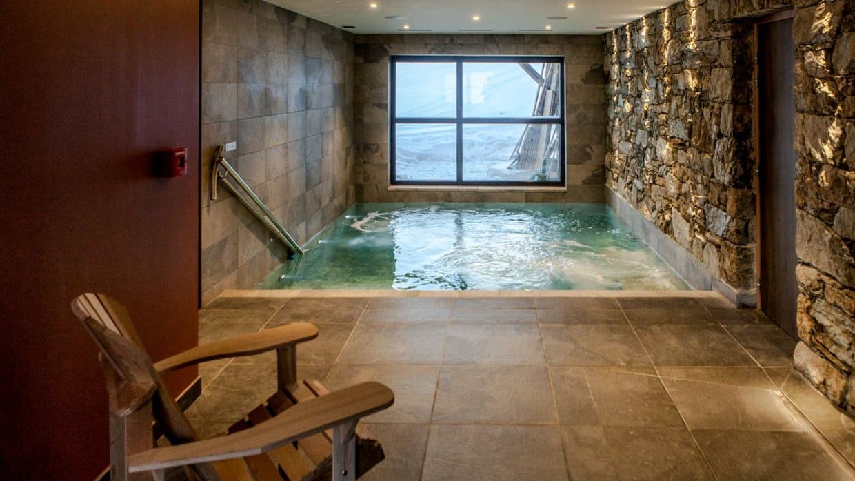 Indoor heated pool with natural stone walls and snow-view window