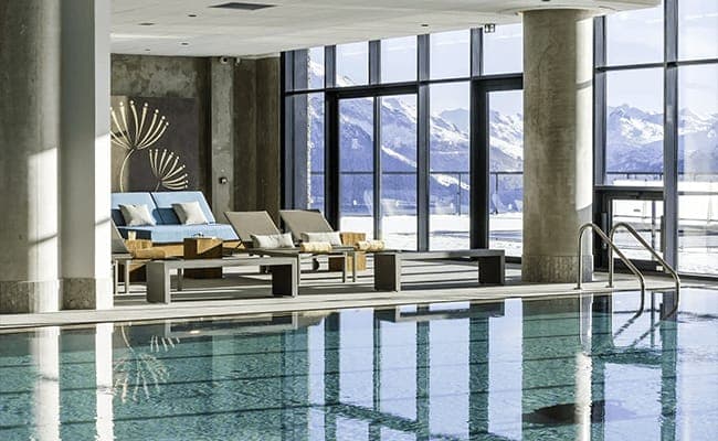 Indoor pool with floor-to-ceiling windows and alpine mountain views