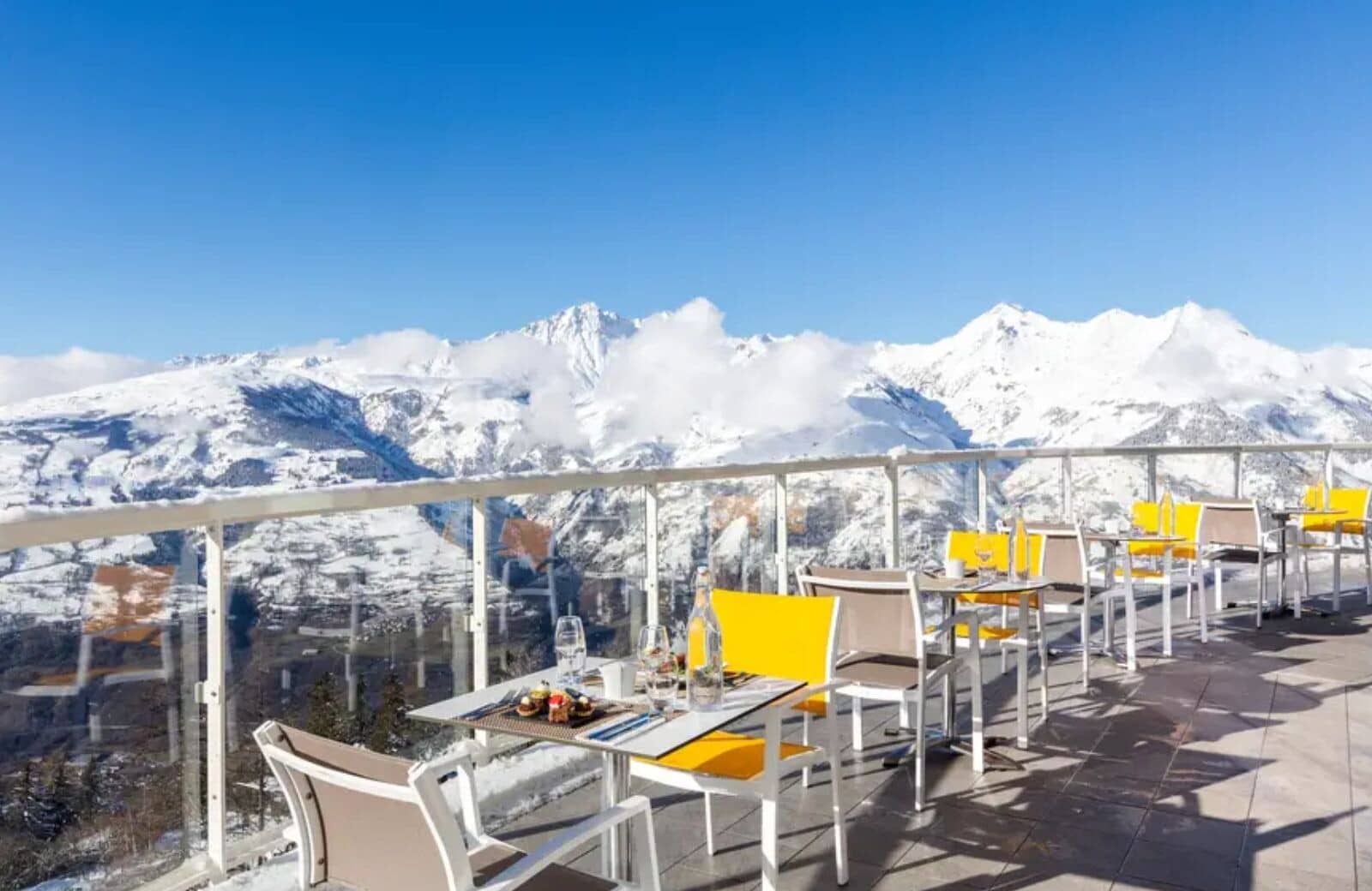 Outdoor terrace seating with glass railings and panoramic alpine views