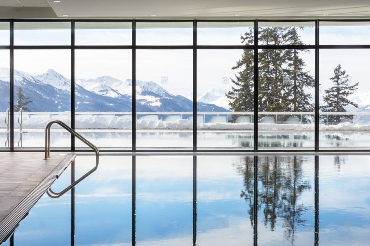 Indoor infinity pool with floor-to-ceiling mountain and forest views