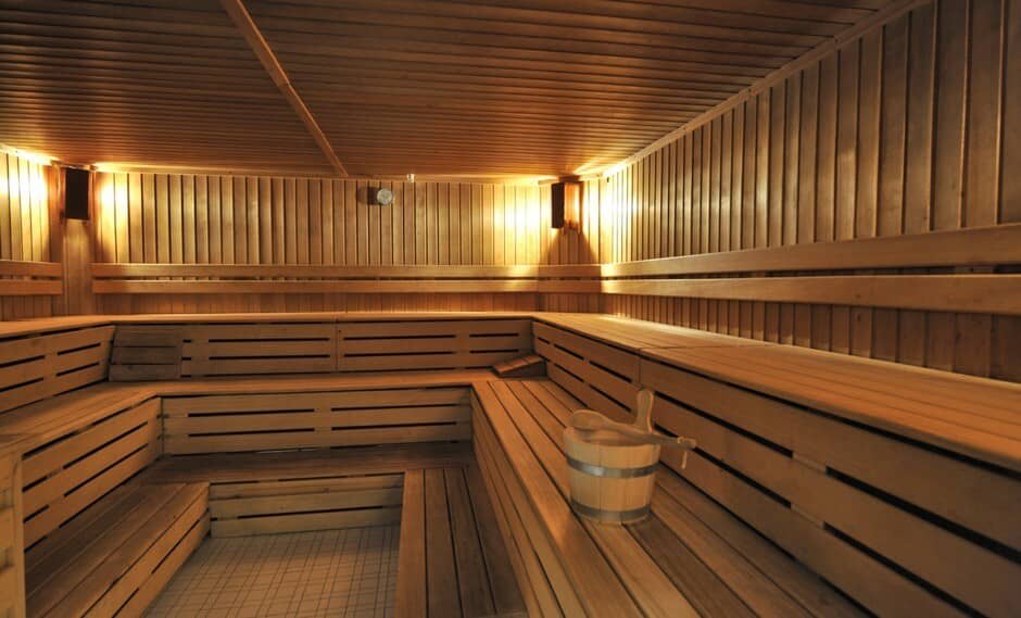 Cedar sauna with tiered bench seating and traditional water bucket